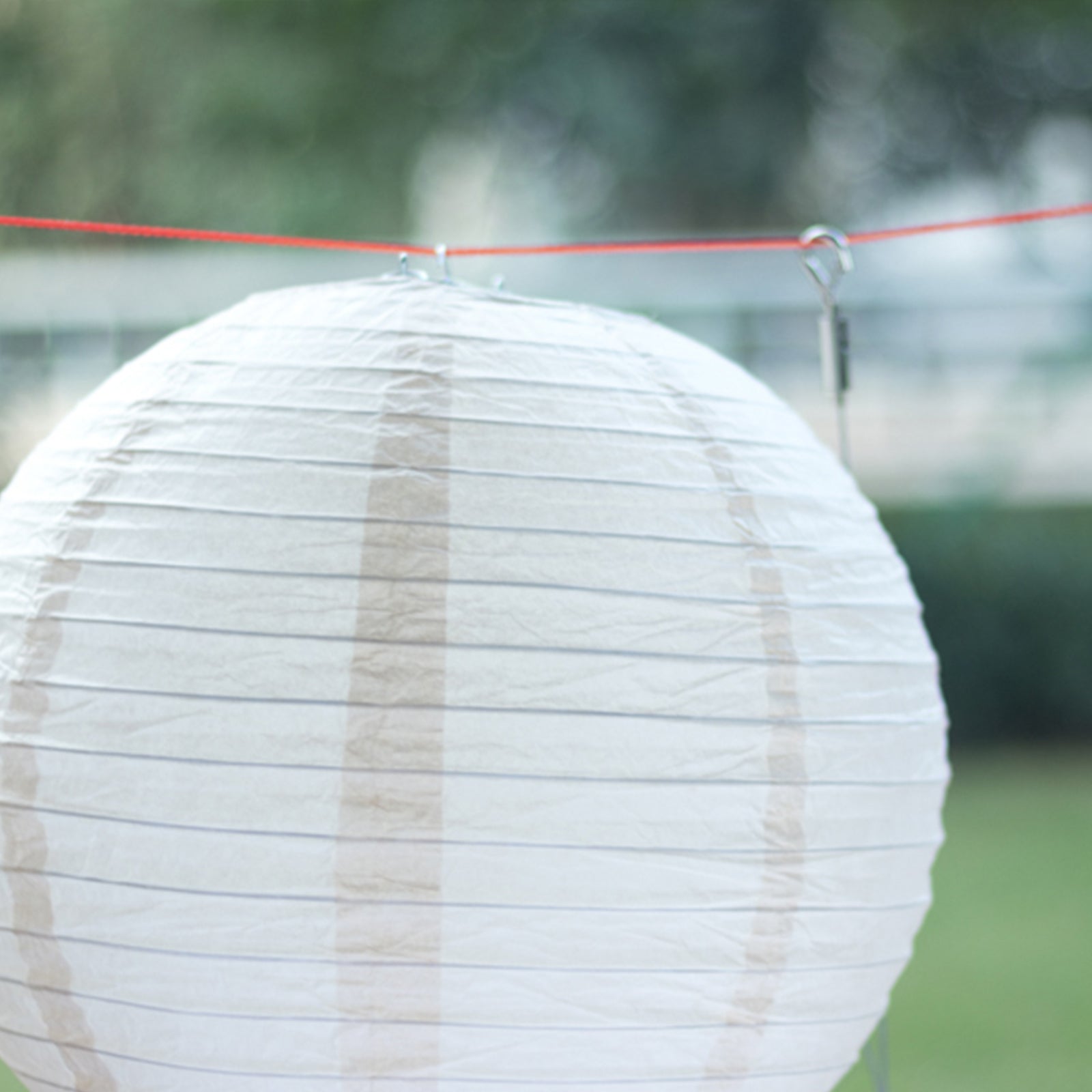 Set of 8 natural brown hanging paper lanterns in assorted sizes.