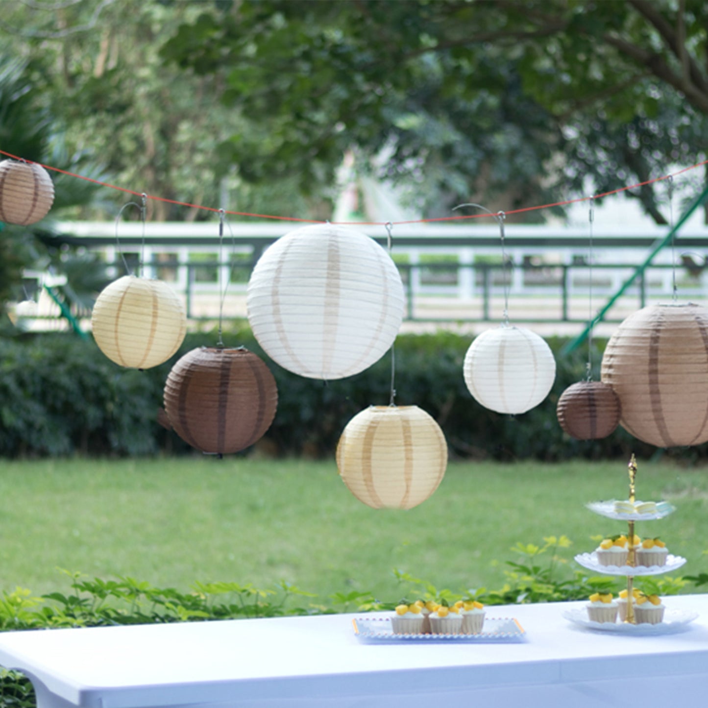Set of 8 natural brown hanging paper lanterns in assorted sizes.
