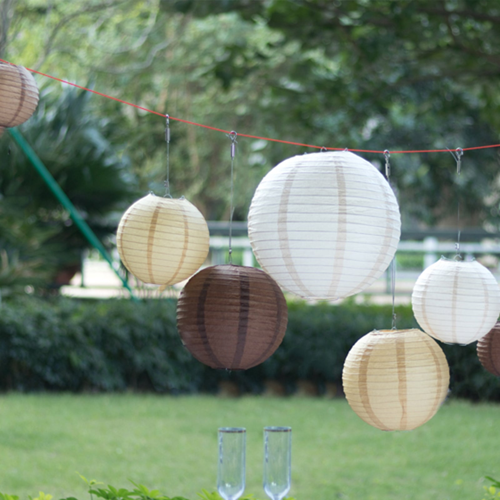 Set of 8 natural brown hanging paper lanterns in assorted sizes.