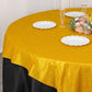 Gold glitter table overlay on a round table with white plates and floral centerpiece.