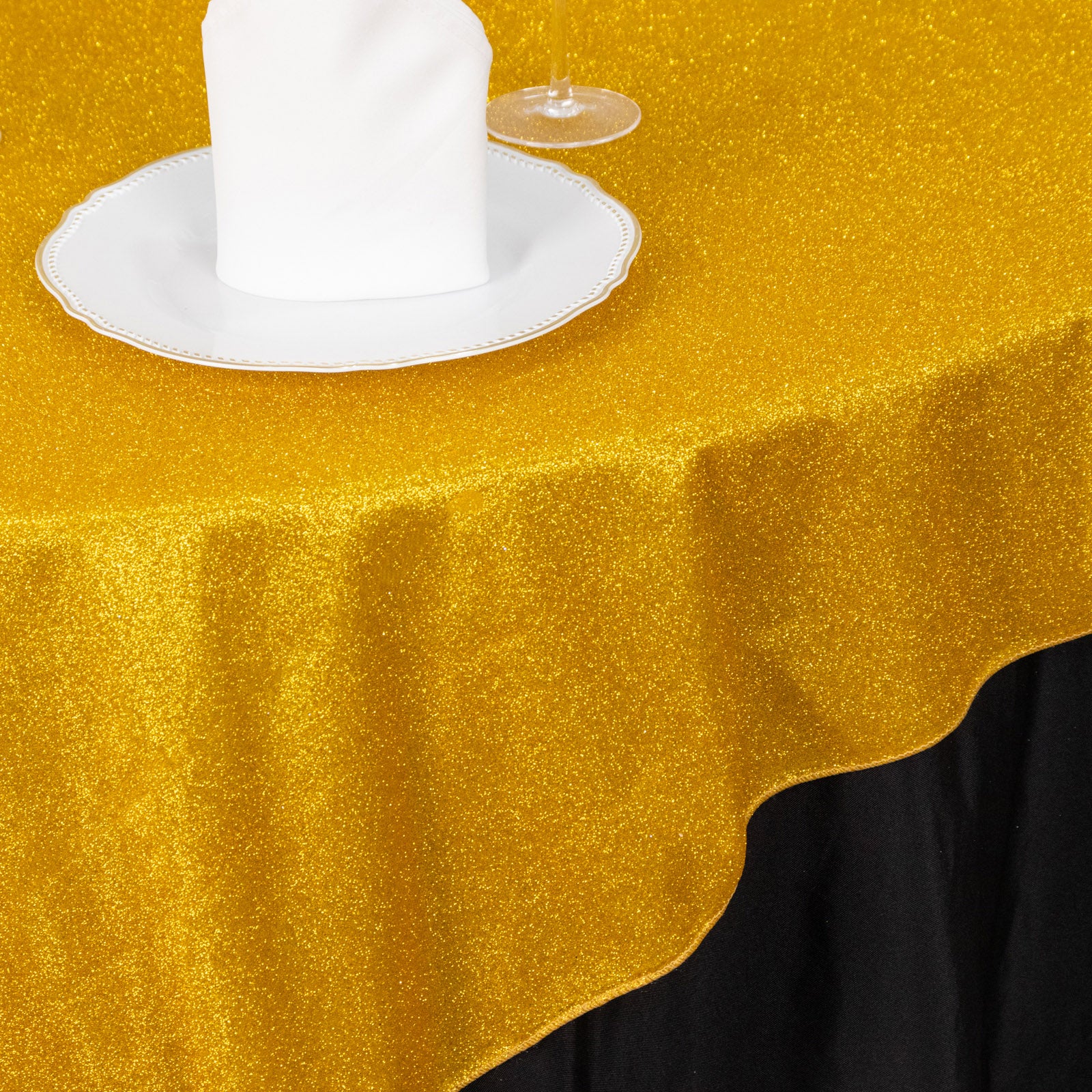 Gold glitter table overlay on a black tablecloth.