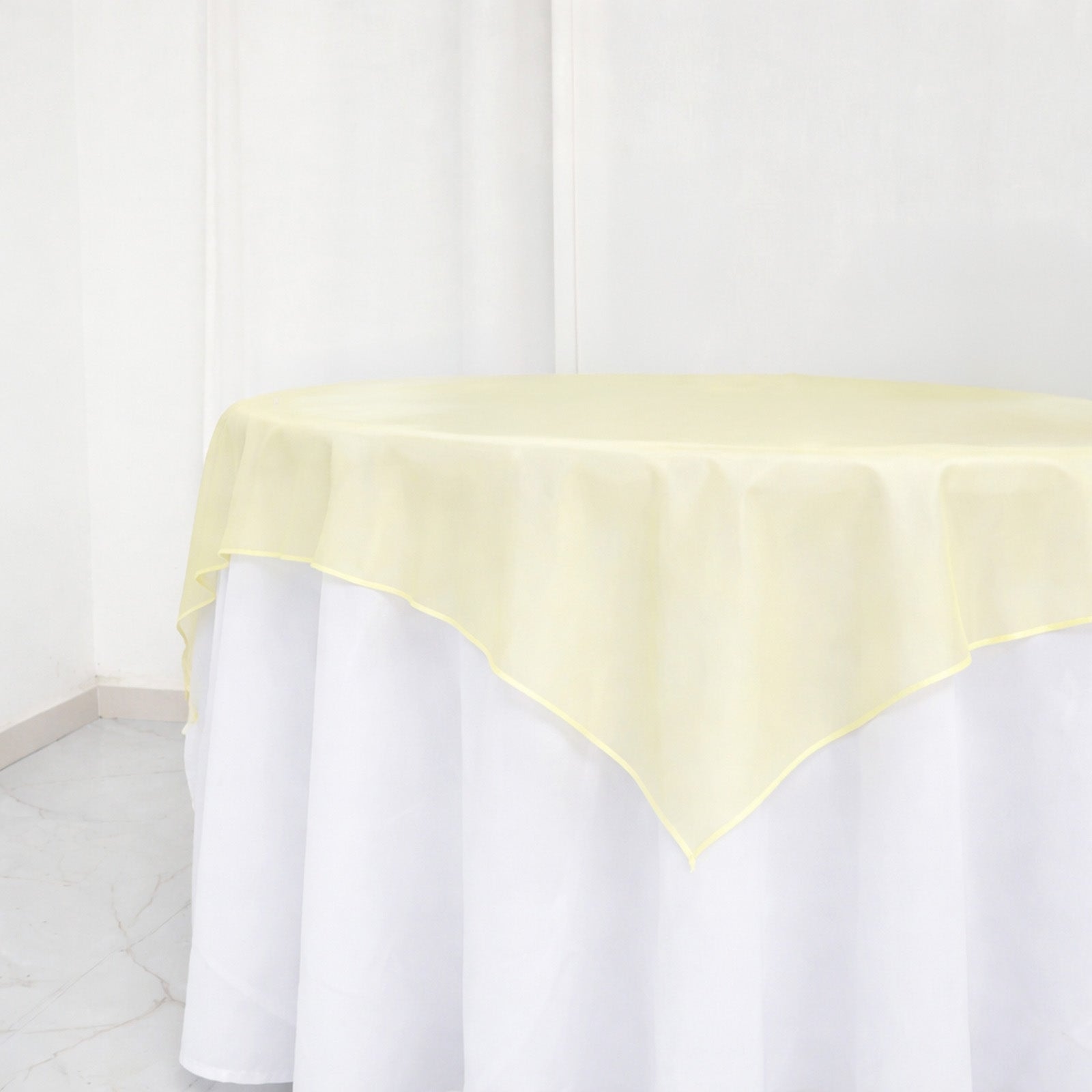 Champagne organza table overlay on a white table, 72"x72".