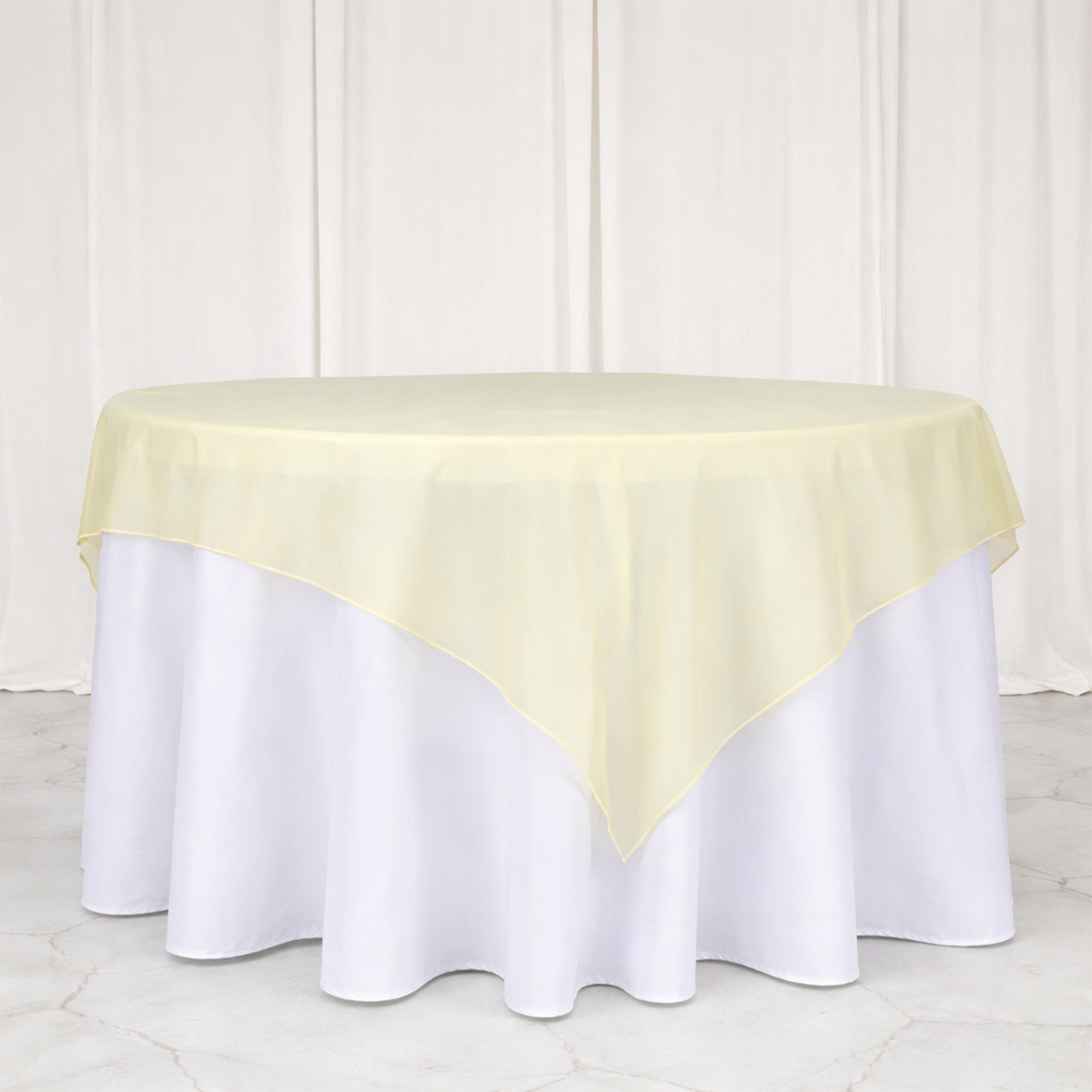 Champagne sheer organza table overlay on a white tablecloth.