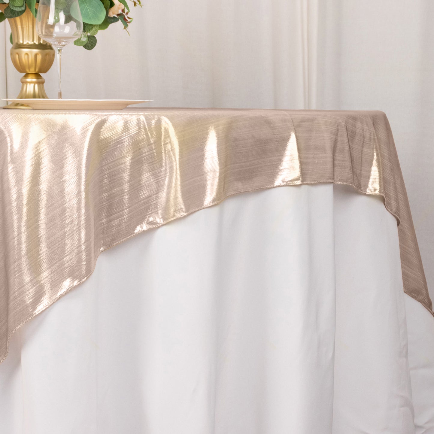 Blush shimmer sequin table overlay on a white tablecloth.