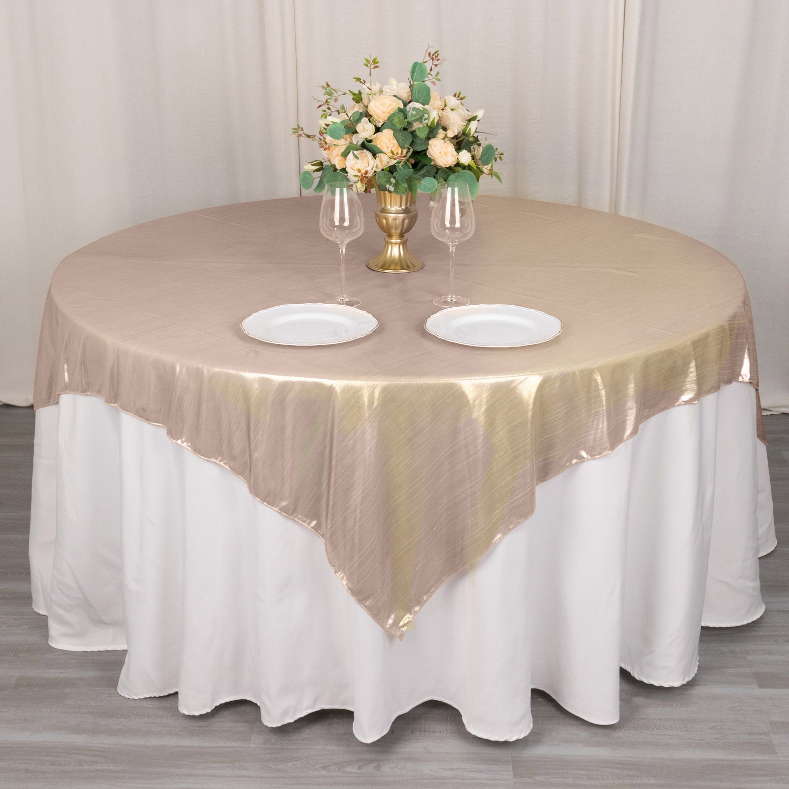 Blush shimmer sequin dots table overlay on a round table with floral centerpiece.