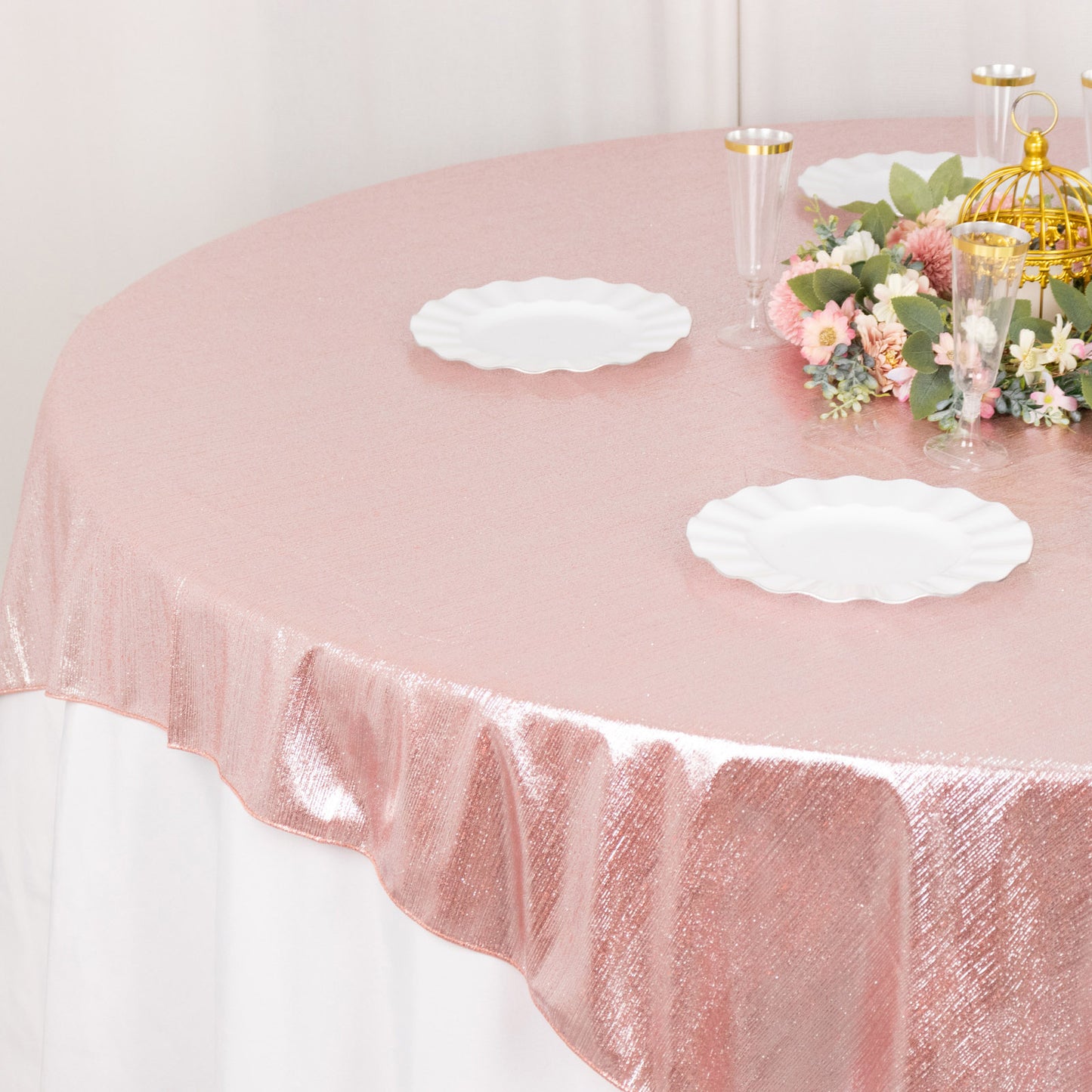 Rose gold shimmer sequin table overlay with floral centerpiece and plates.