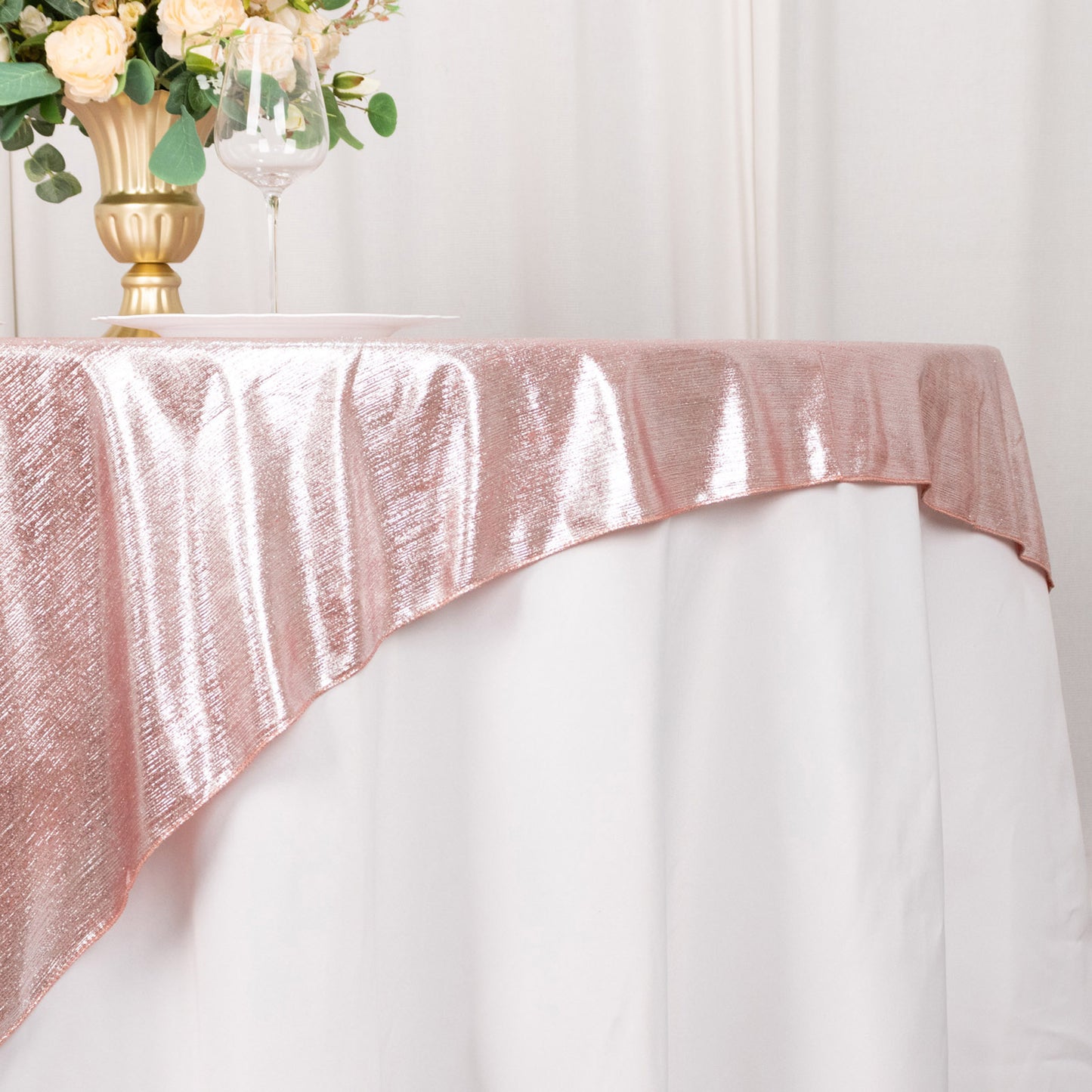 Rose gold sequin table overlay on a white table.