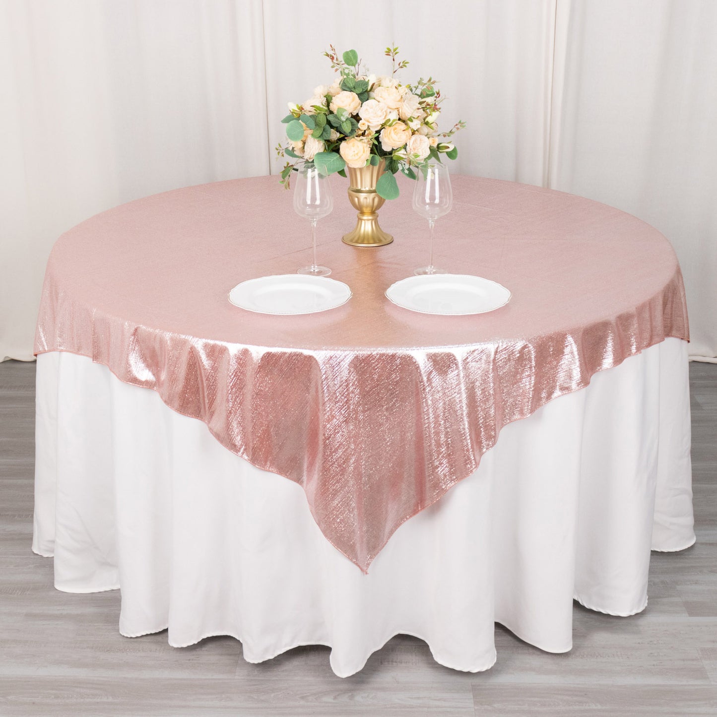 Rose gold sequin table overlay with floral centerpiece and dinnerware.