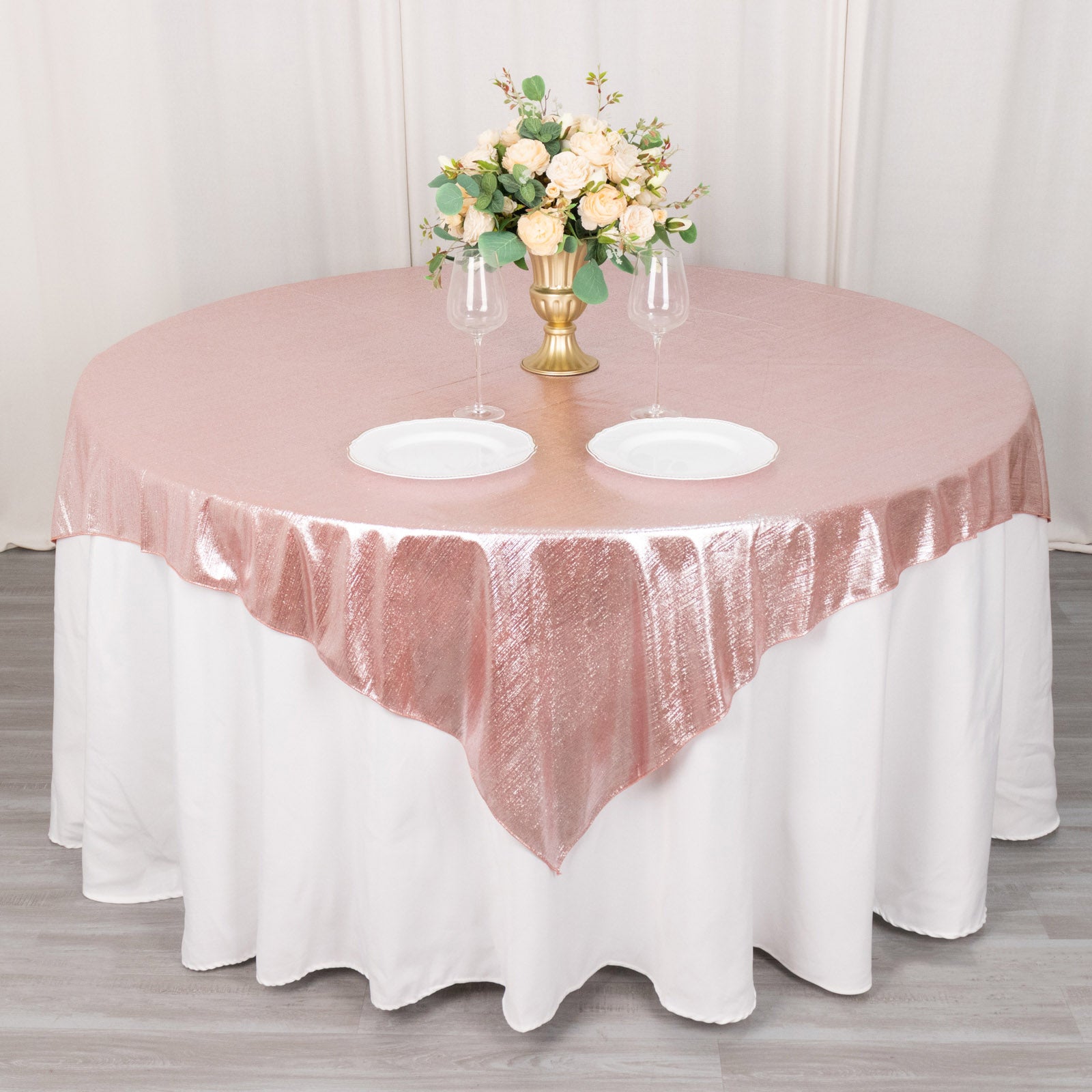 Rose gold sequin table overlay with floral centerpiece and dinnerware.