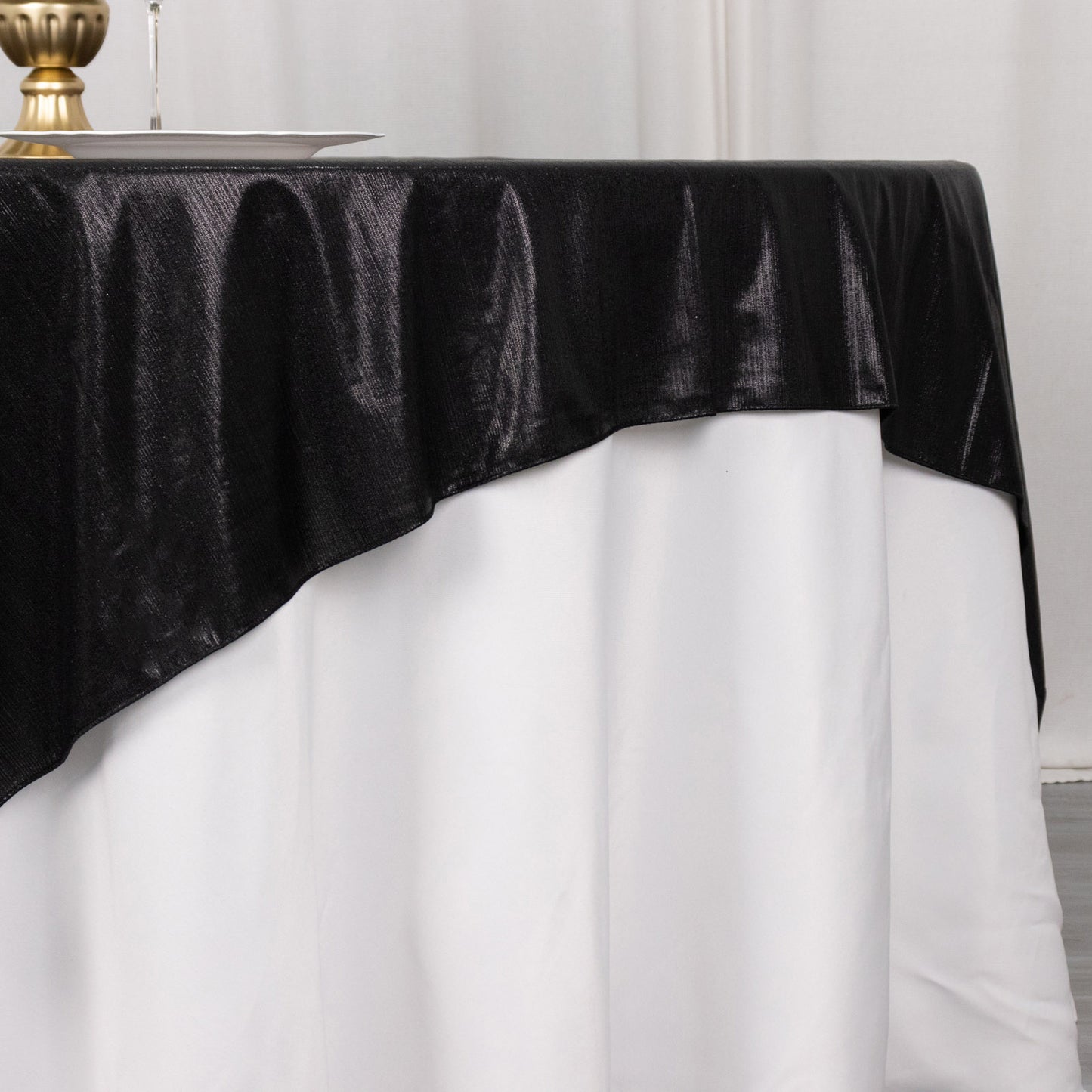 Black shimmer sequin dots table overlay on a white tablecloth.