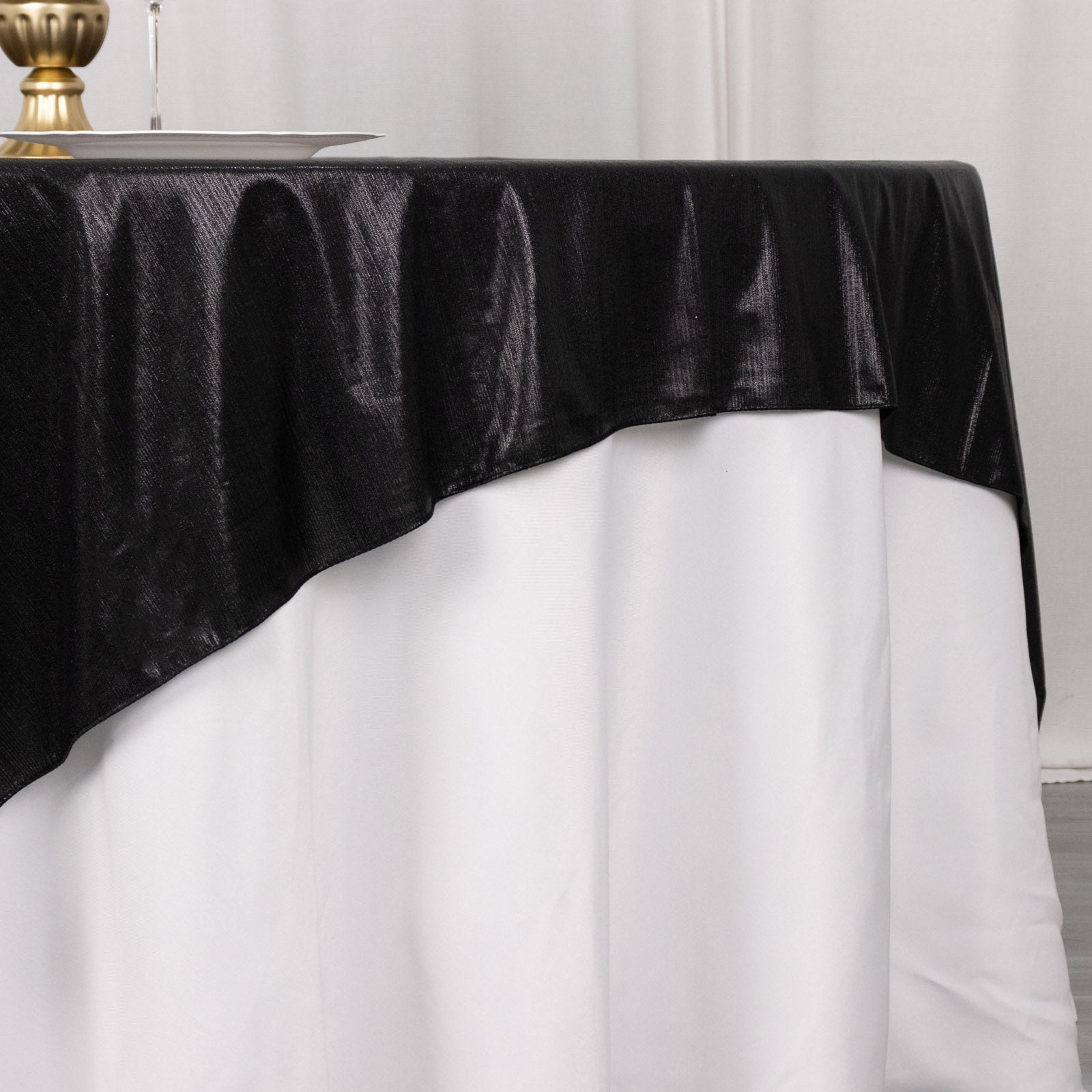 Black shimmer sequin dots table overlay on a white tablecloth.