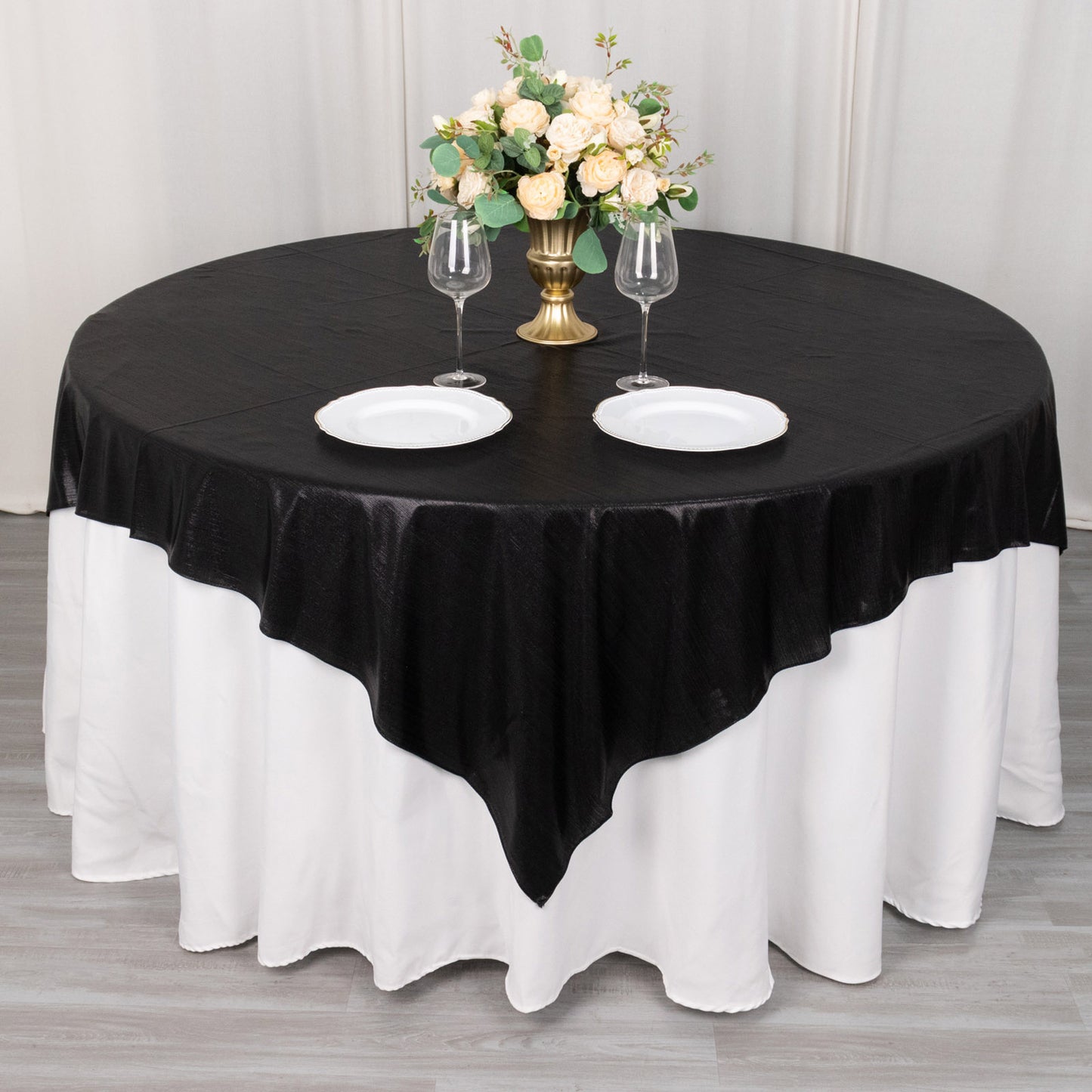Black shimmer sequin dots table overlay on a round table with floral centerpiece.