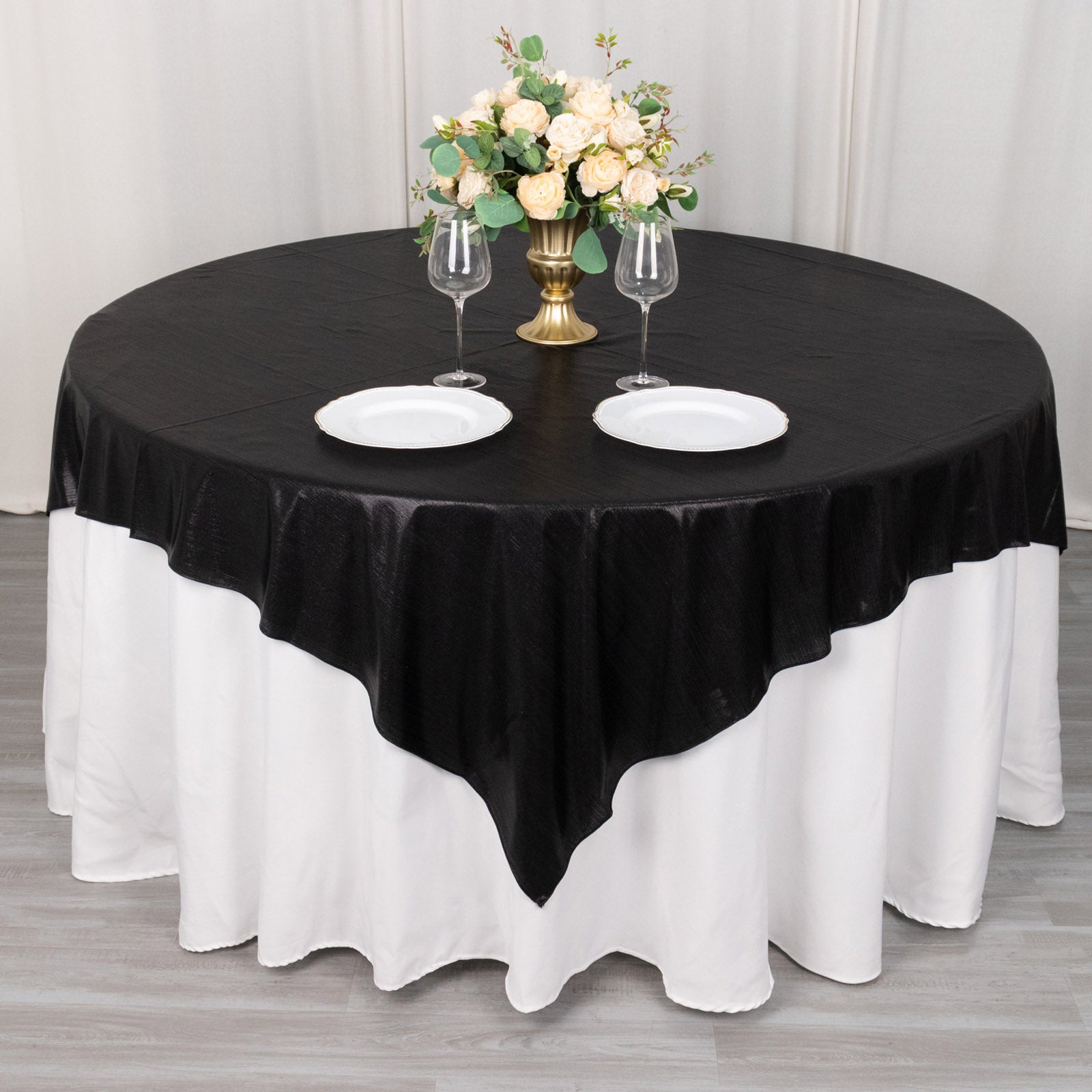 Black shimmer sequin dots table overlay on a round table with floral centerpiece.