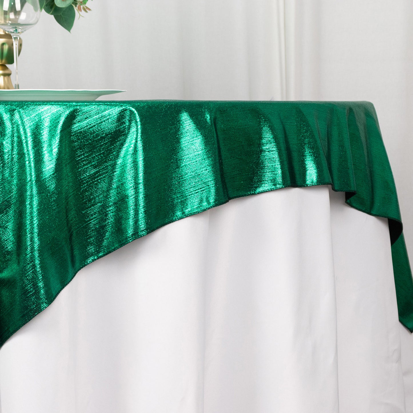 Hunter emerald green shimmer sequin table overlay on a white table.