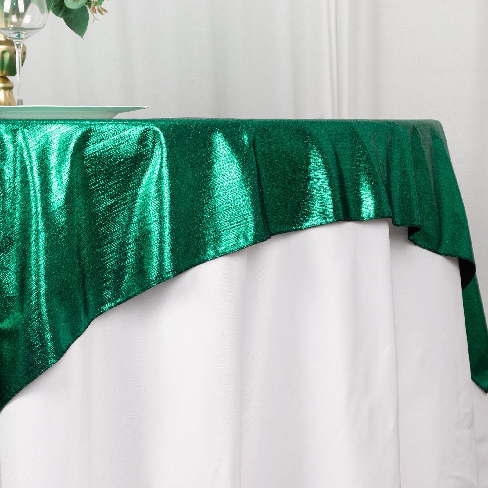 Hunter emerald green shimmer sequin table overlay on a white table.