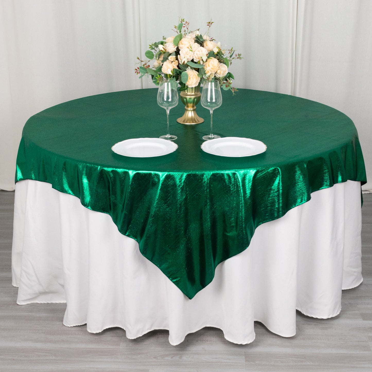 Emerald green shimmer sequin table overlay on round table with floral centerpiece.