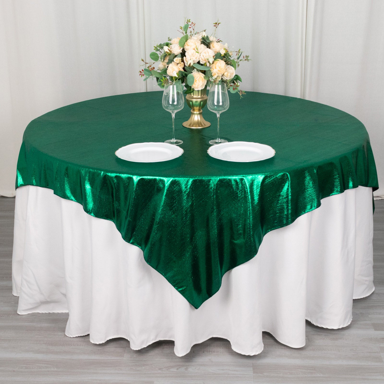 Emerald green shimmer sequin table overlay on round table with floral centerpiece.