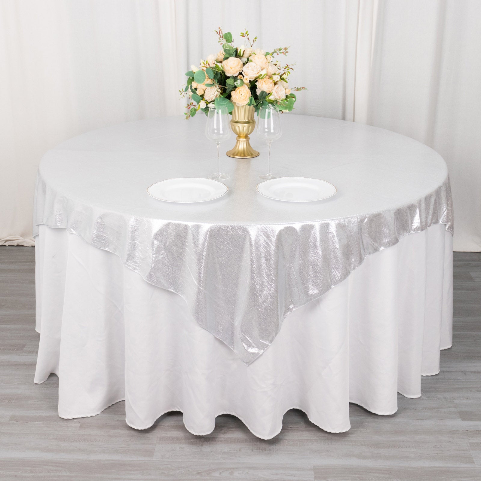 Silver shimmer sequin table overlay on a round table with floral centerpiece.