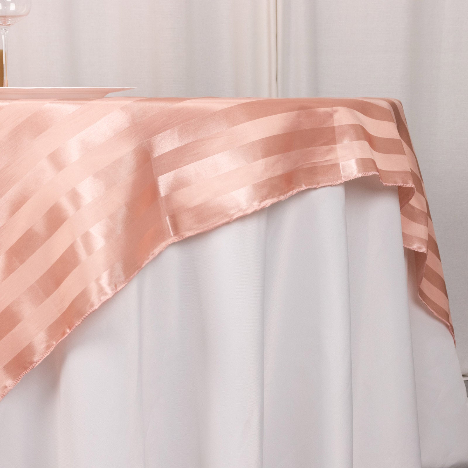 Dusty rose satin stripe table overlay on a white tablecloth.