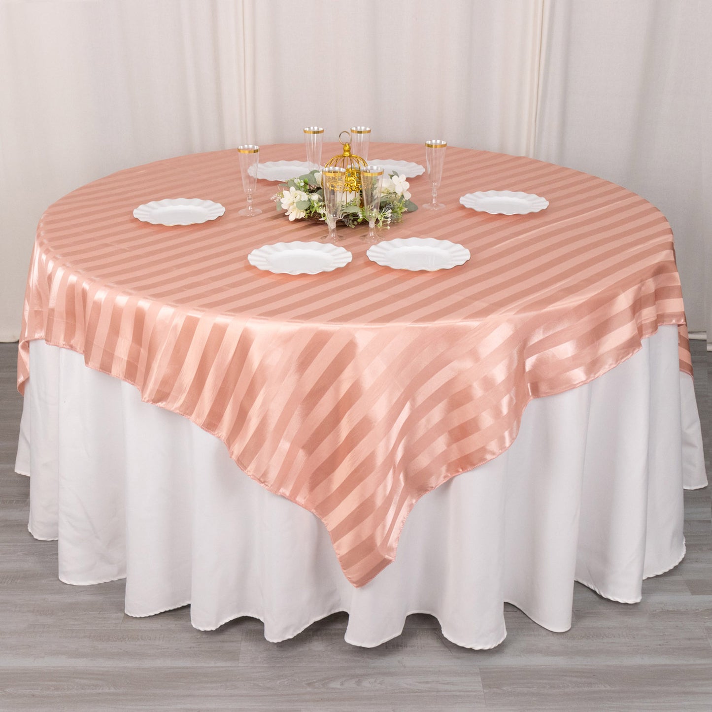 Dusty rose satin stripe table overlay on a round table.