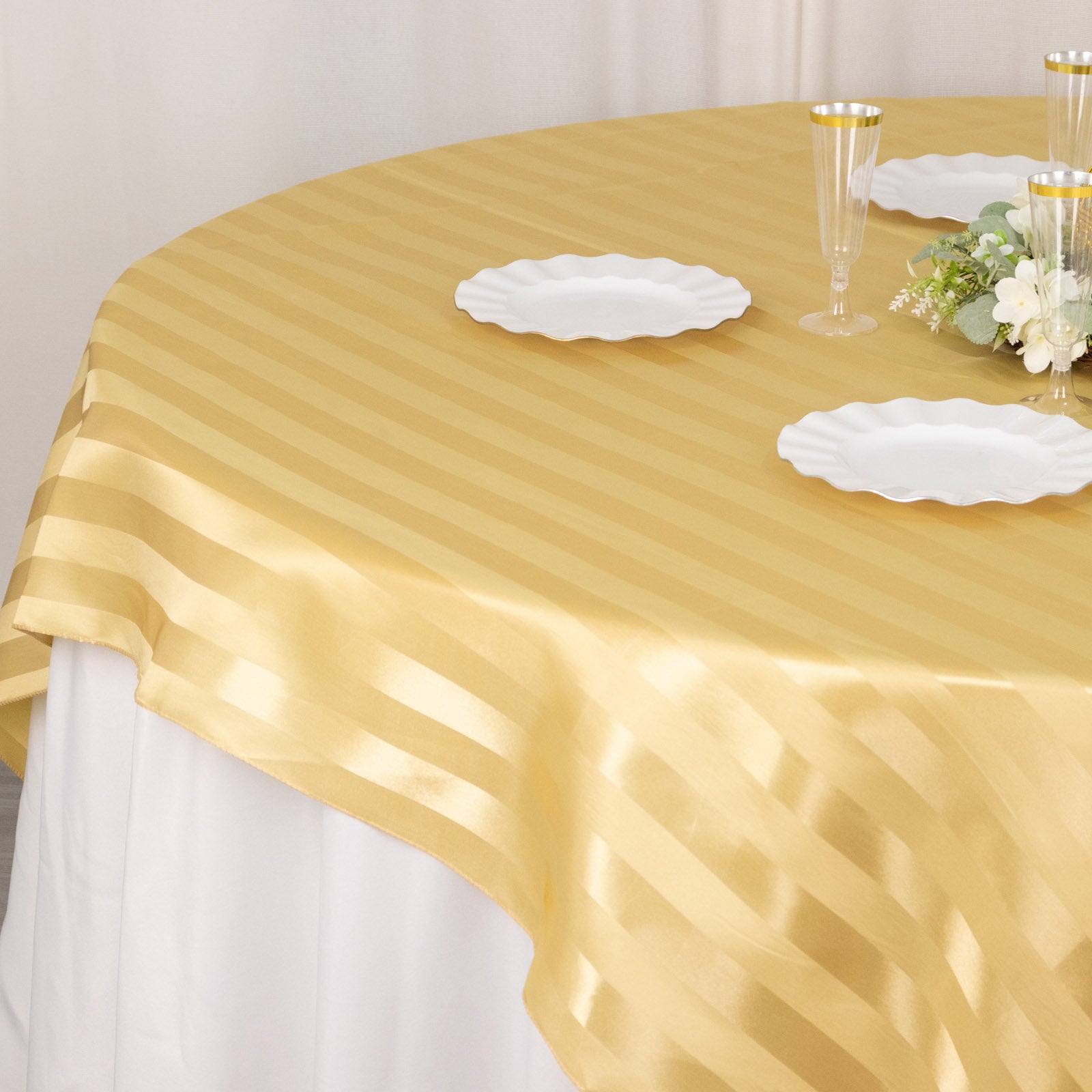 Champagne satin stripe table overlay on a round table setting.