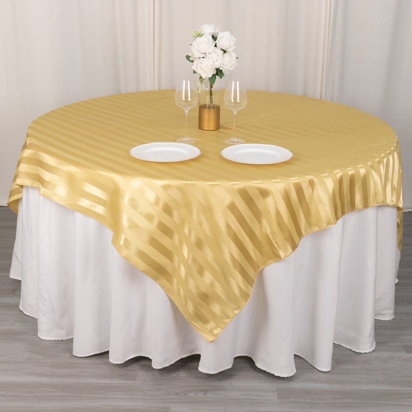 Champagne satin stripe table overlay on a round table with floral centerpiece.
