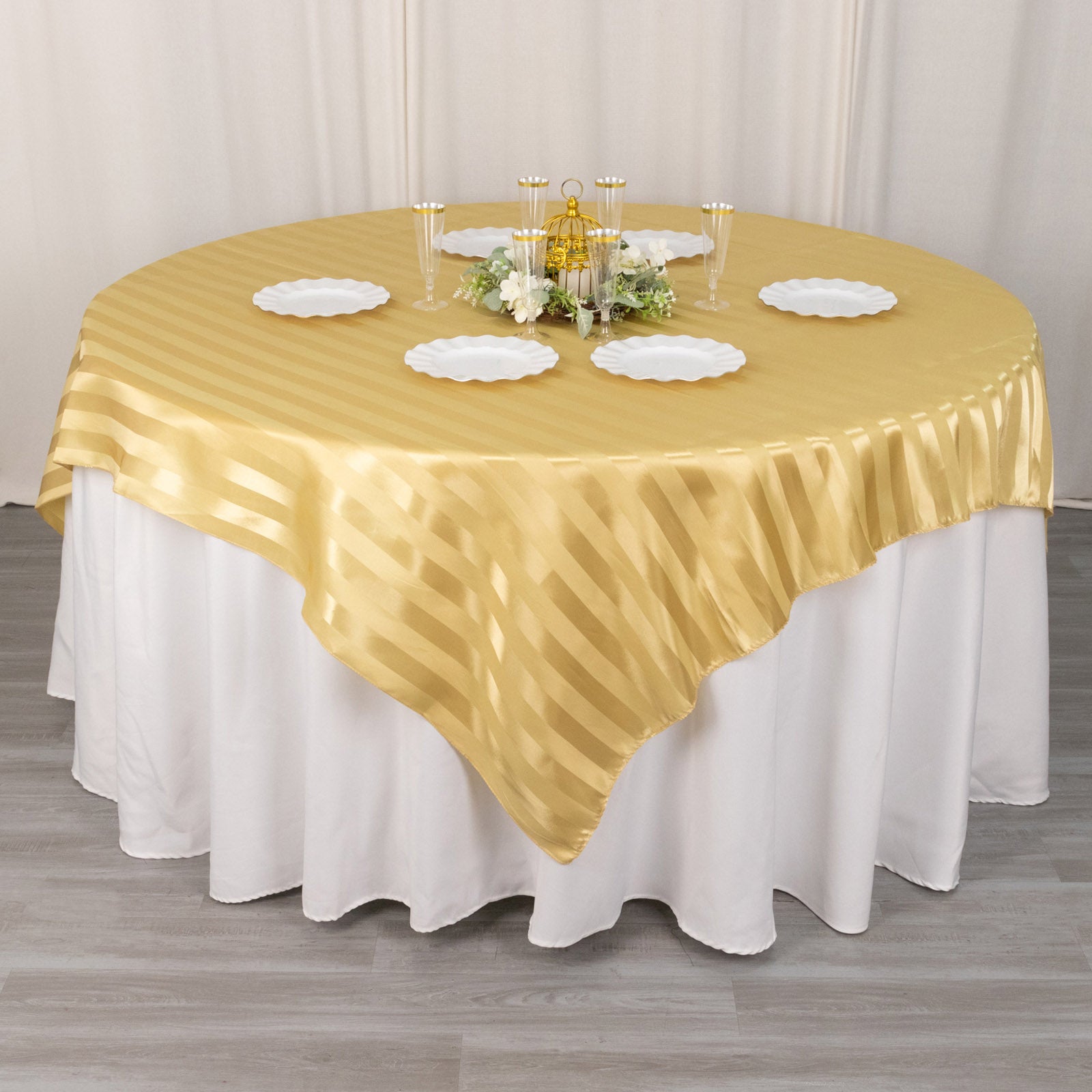 Champagne satin stripe table overlay on a round table setting.