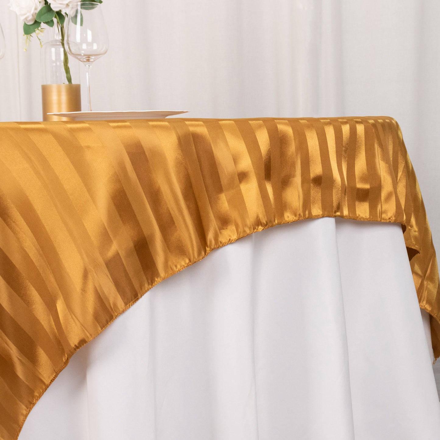 Gold satin stripe table overlay on a white table.
