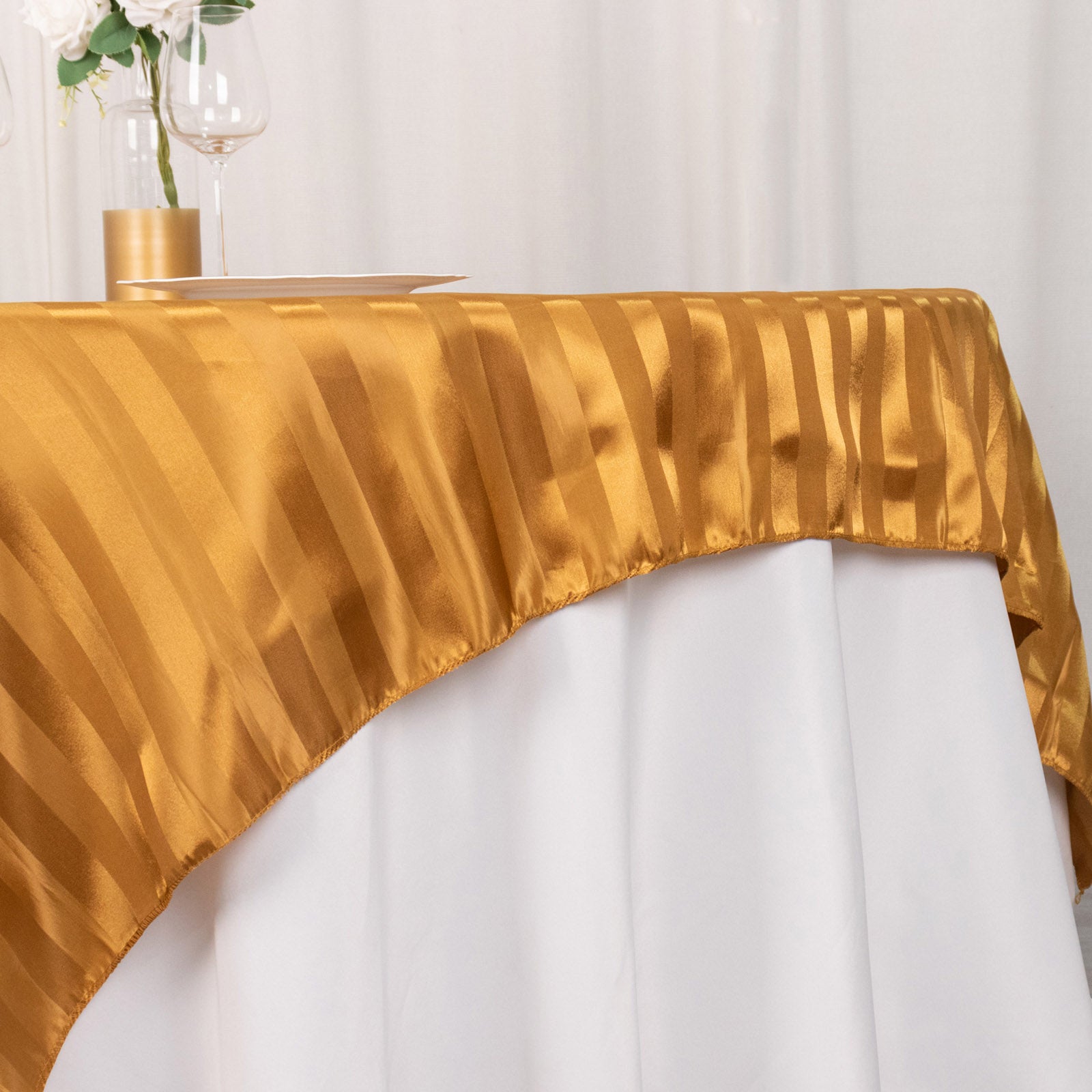 Gold satin stripe table overlay on a white table.