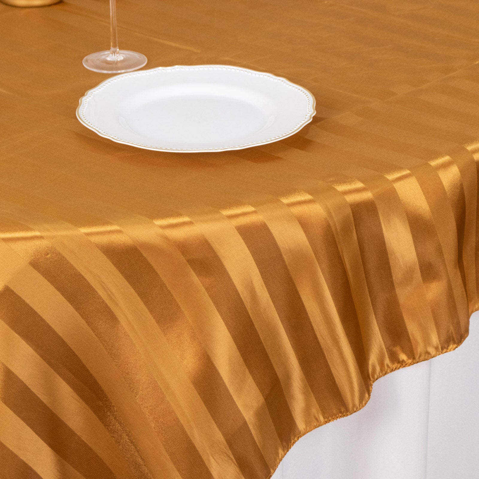Gold satin stripe table overlay on a smooth table surface.