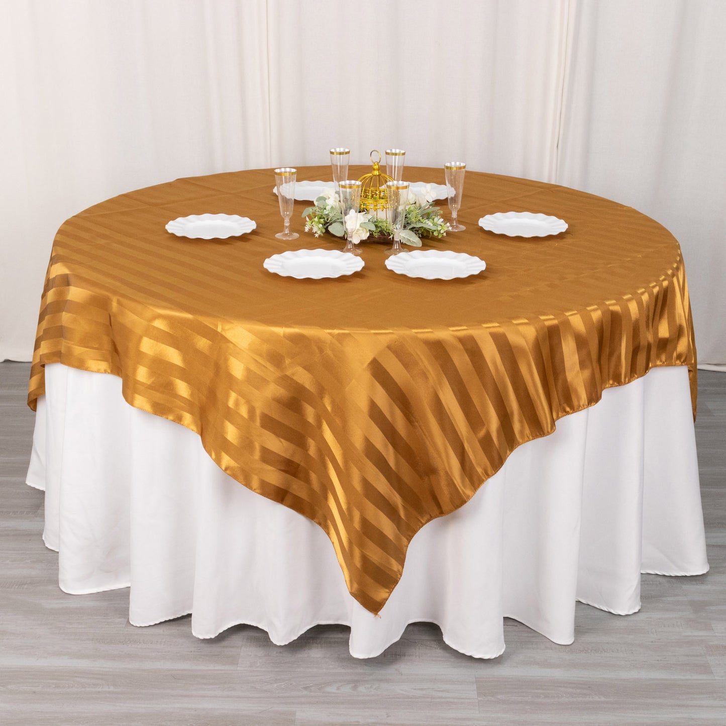 Gold satin stripe table overlay on a round table setting.