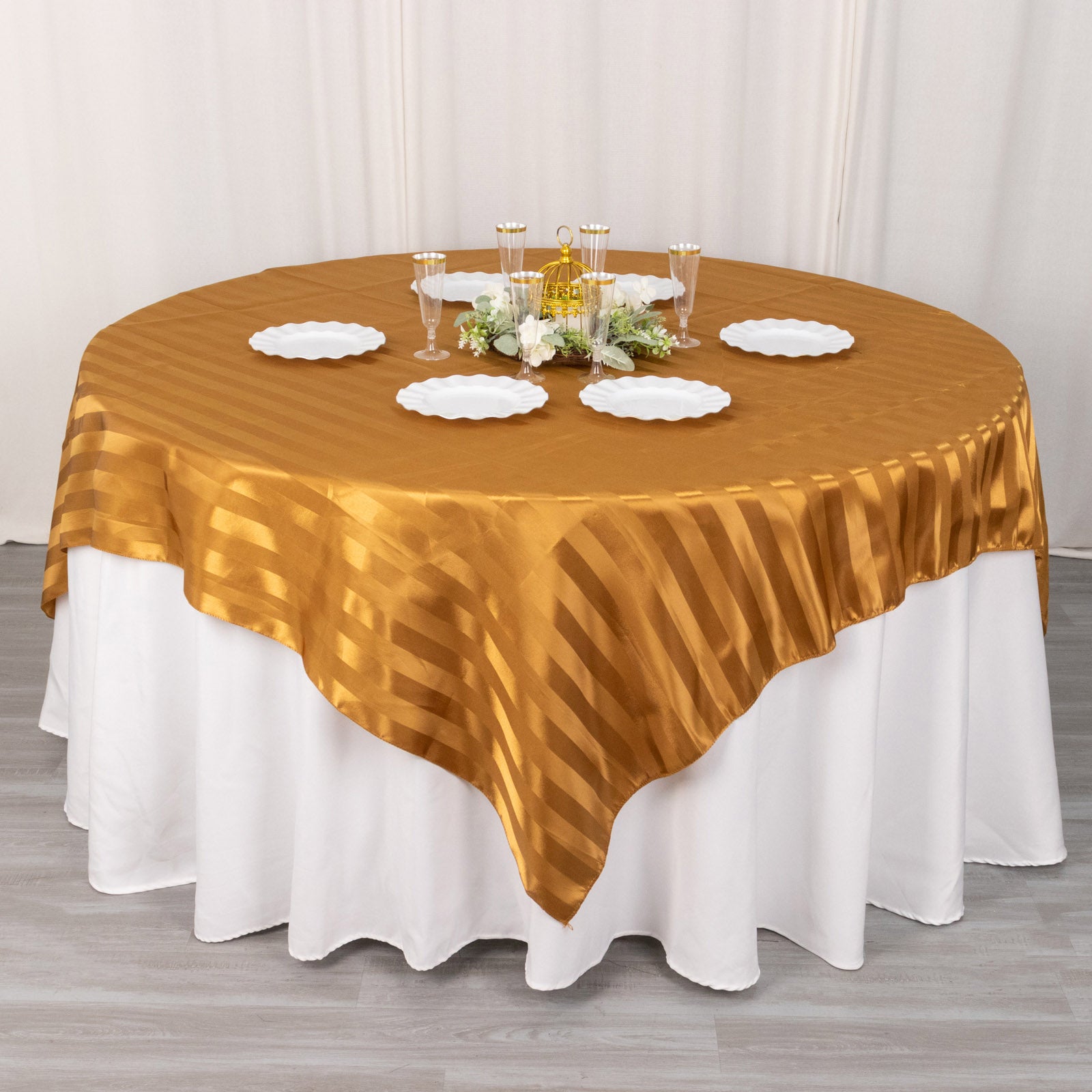 Gold satin stripe table overlay on a round table setting.