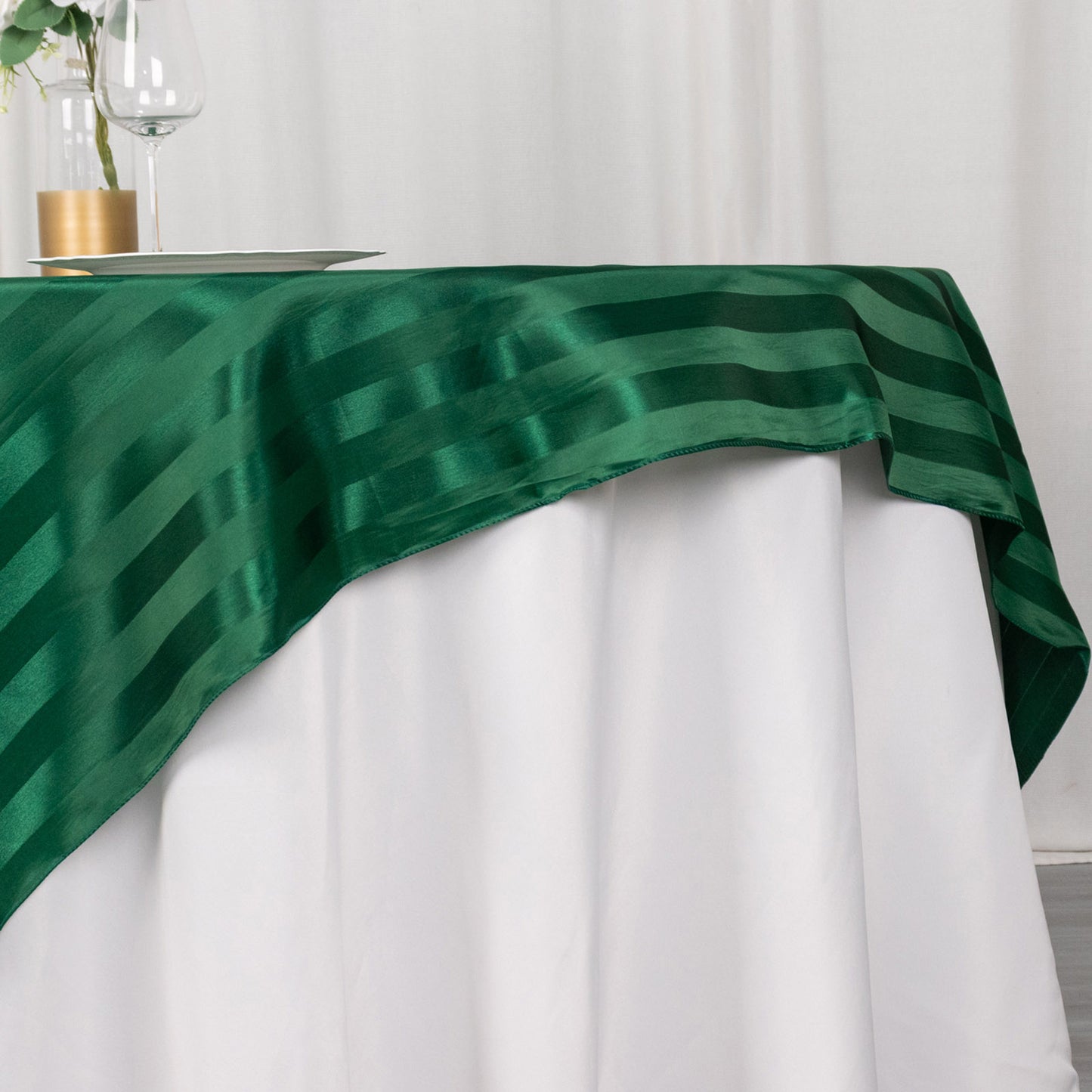 72"x72" hunter emerald green satin stripe table overlay on a white table.