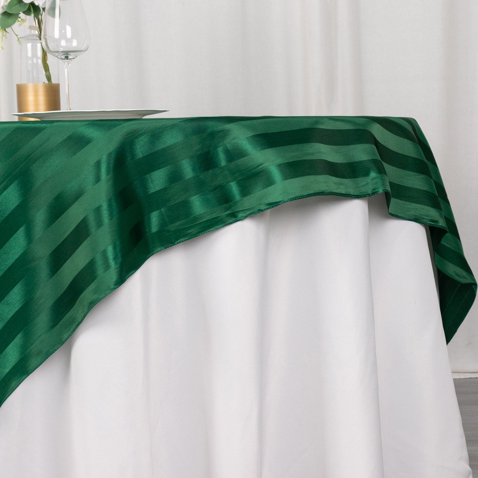 72"x72" hunter emerald green satin stripe table overlay on a white table.