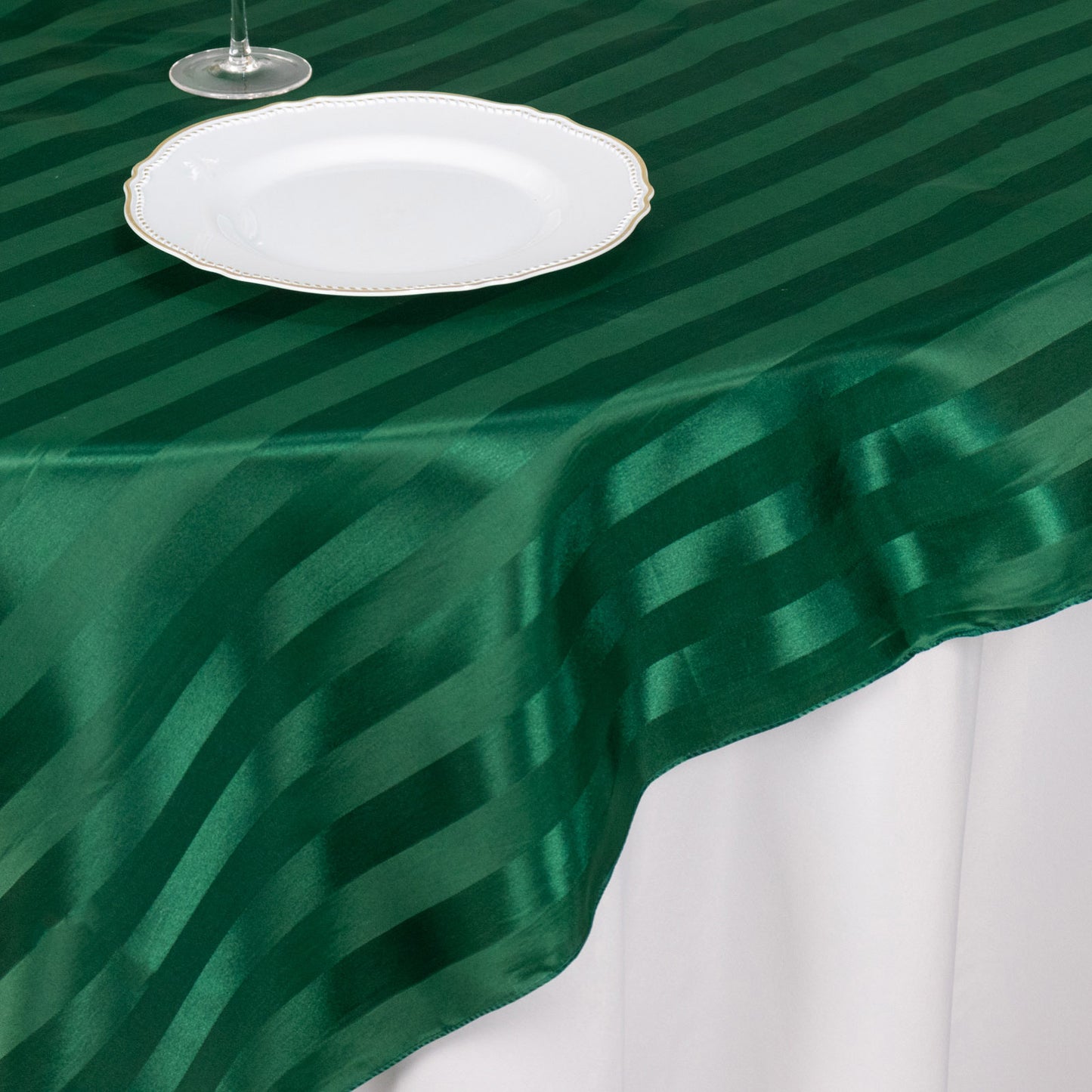 72"x72" hunter emerald green satin stripe table overlay on a white table.