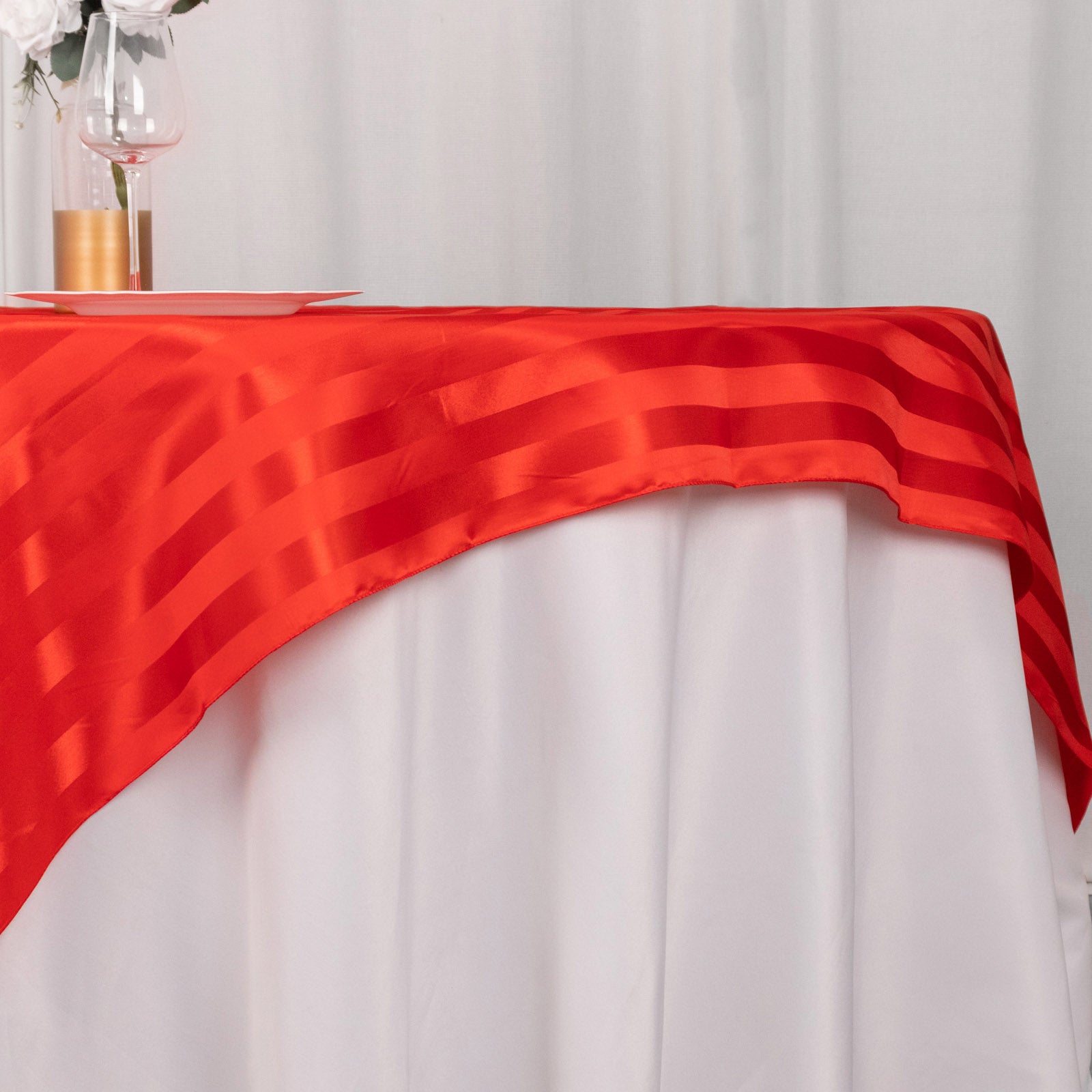 Red satin stripe table overlay on a white tablecloth.