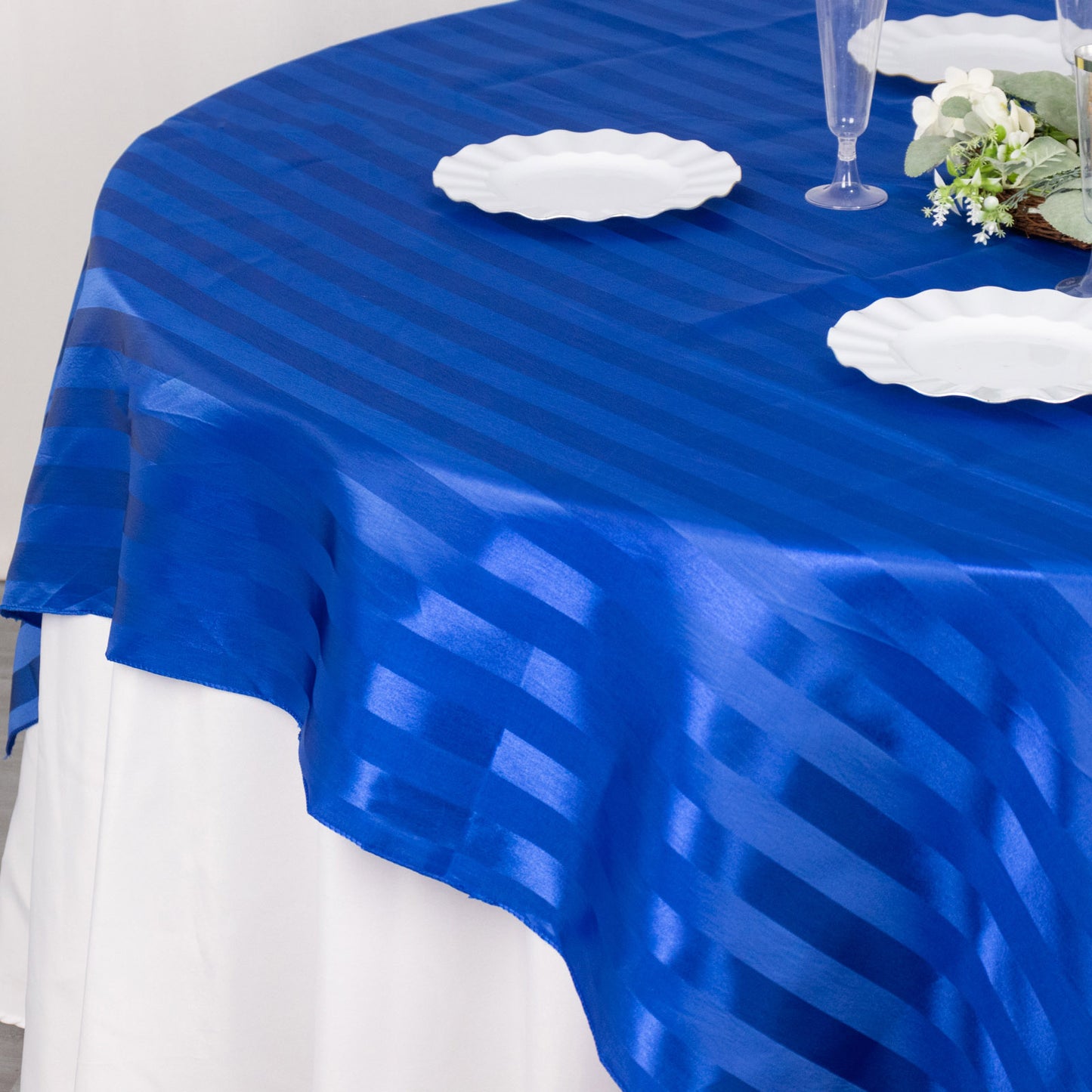 72"x72" royal blue satin stripe table overlay on a white tablecloth.
