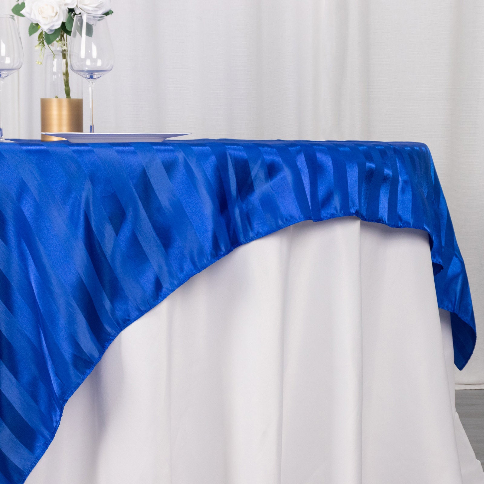 Royal blue satin stripe table overlay on a smooth table surface.