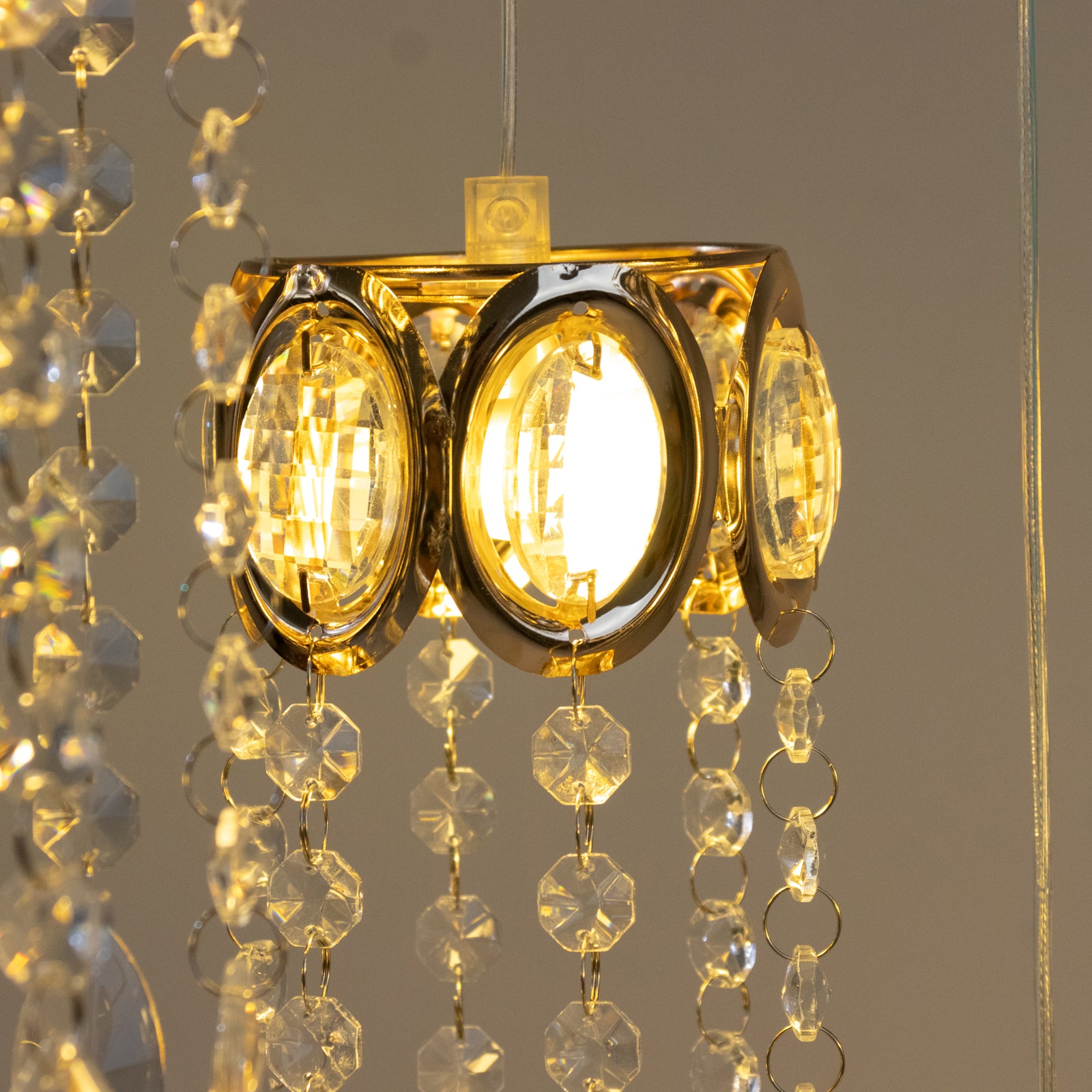 Gold oval frame with teardrop pendants in warm white light.
