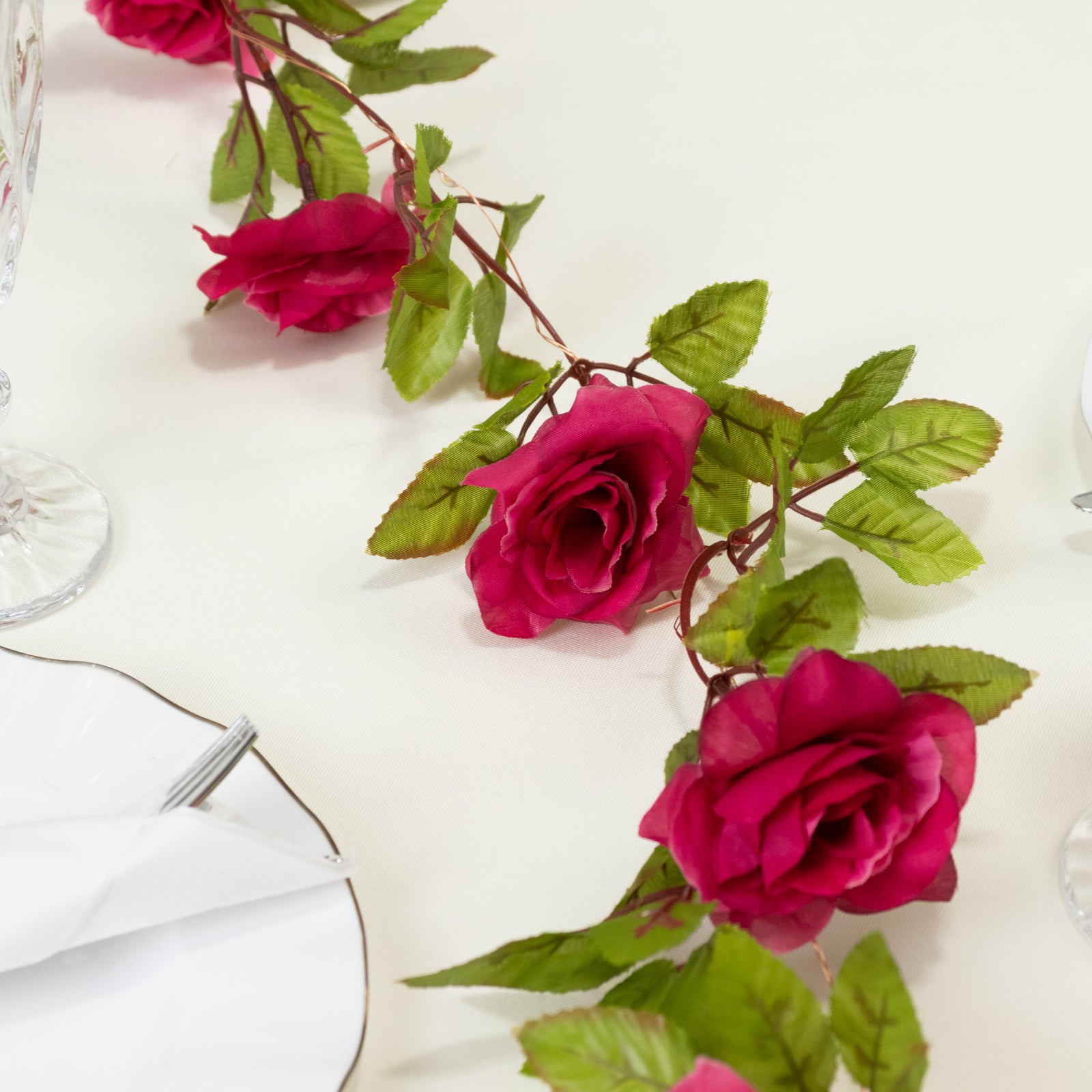 Magenta silk rose flower garland vine string lights on a table.