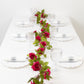 Red silk rose flower garland vine string lights on a table setting.