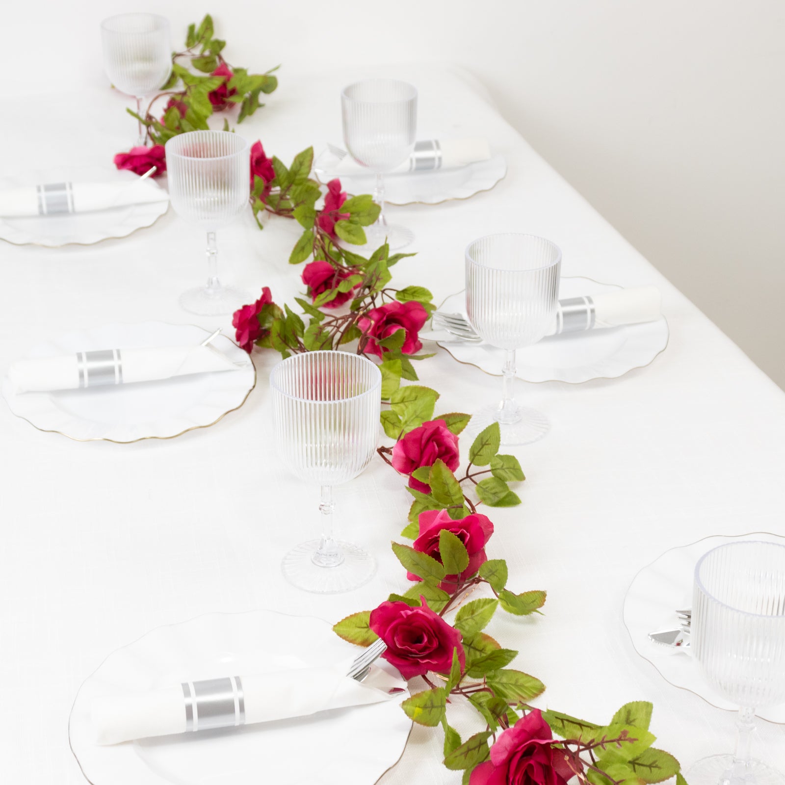 Red silk rose flower garland vine string lights on a table setting.