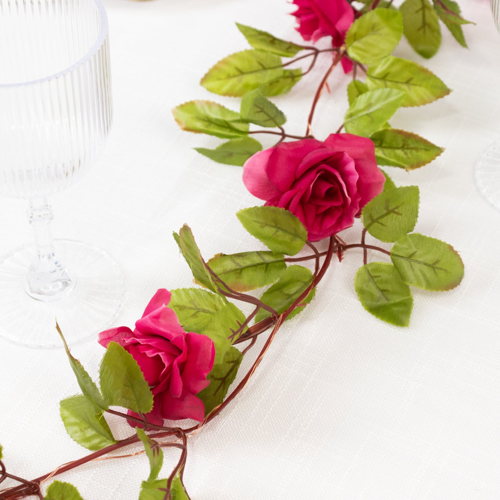 Red silk rose flower garland vine string lights with green leaves.
