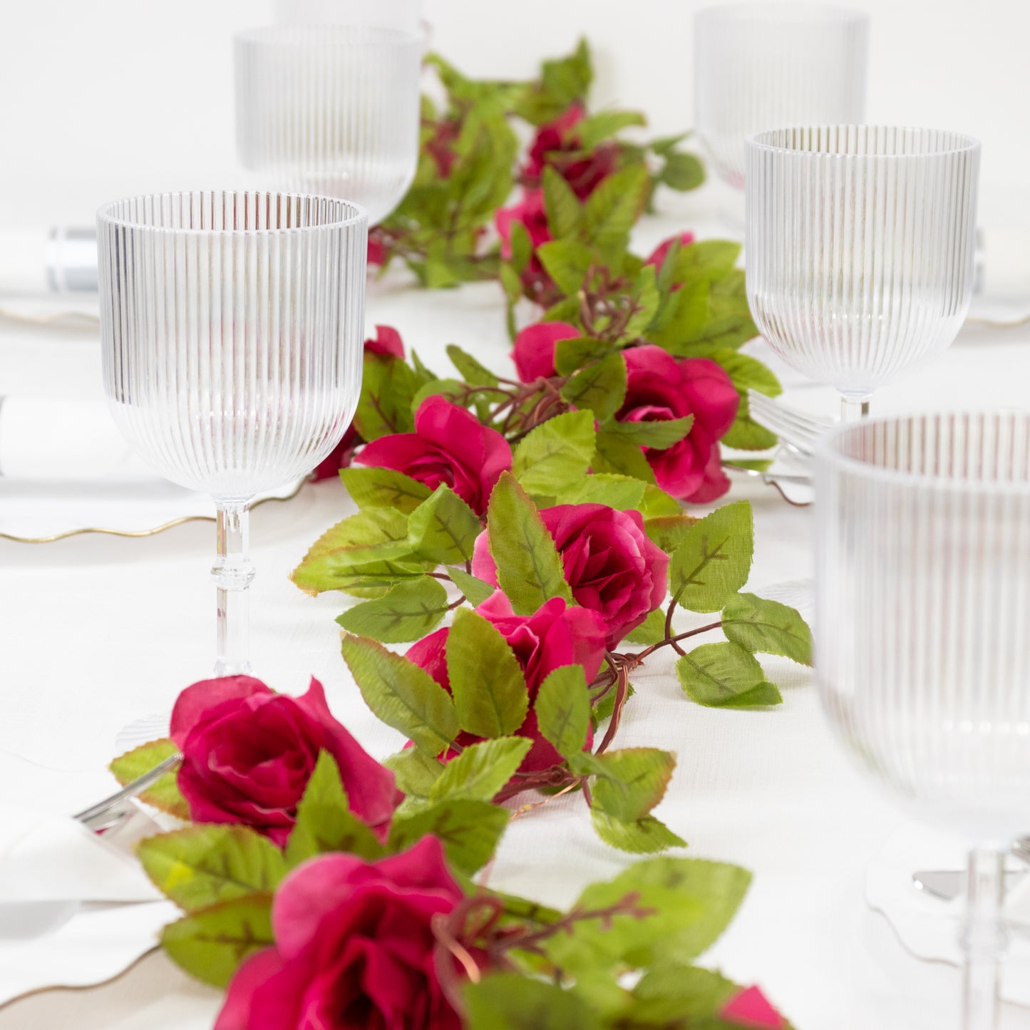 Red silk rose flower garland vine string lights on a table setting.