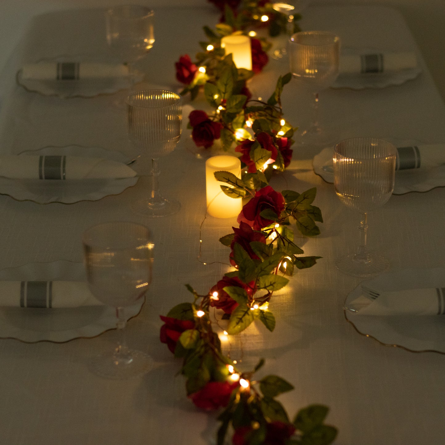 Red silk rose flower garland vine string lights with warm white glow.