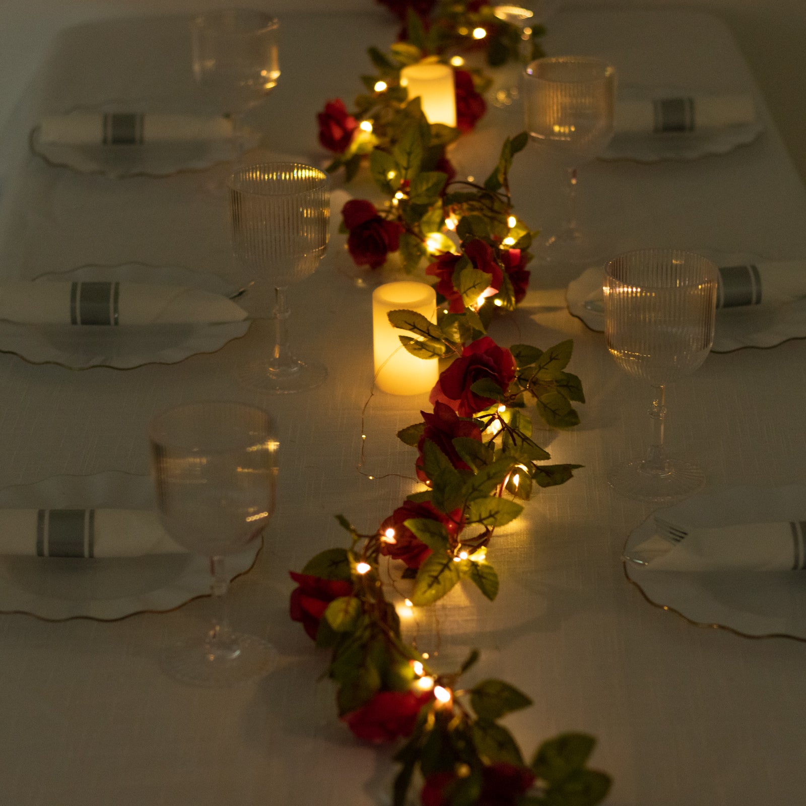 Red silk rose flower garland vine string lights with warm white glow.