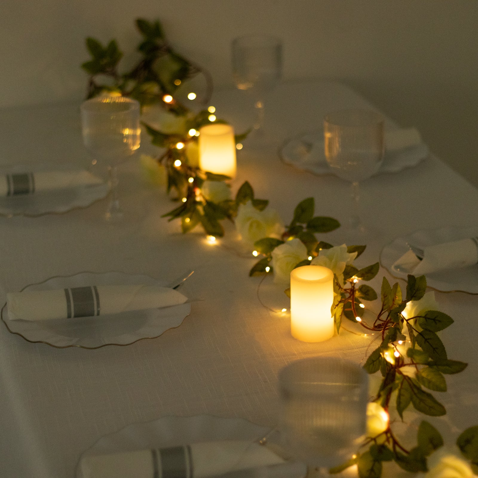 Warm white silk rose flower garland vine string lights on a table setting.