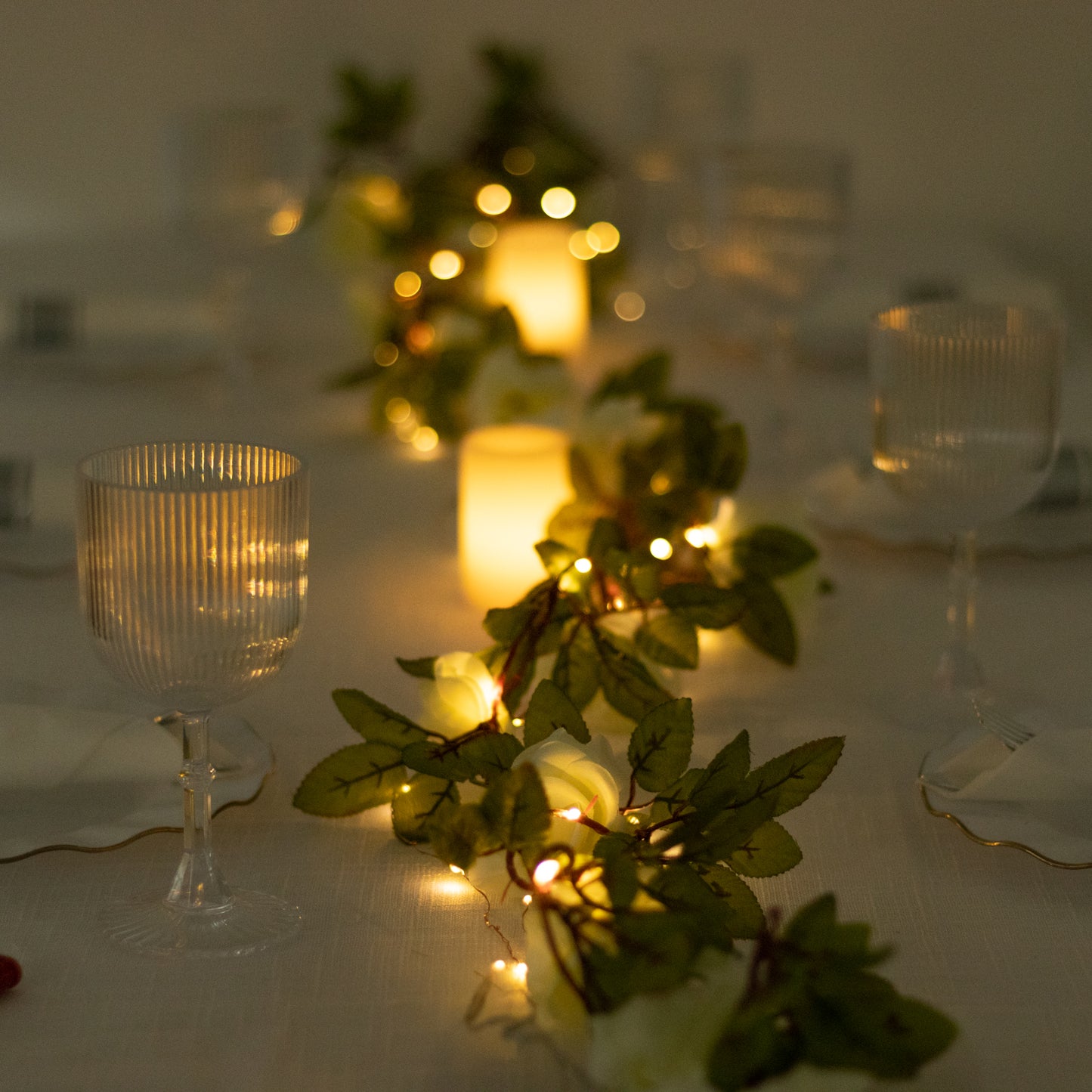 Warm white silk rose flower garland vine string lights on a table.