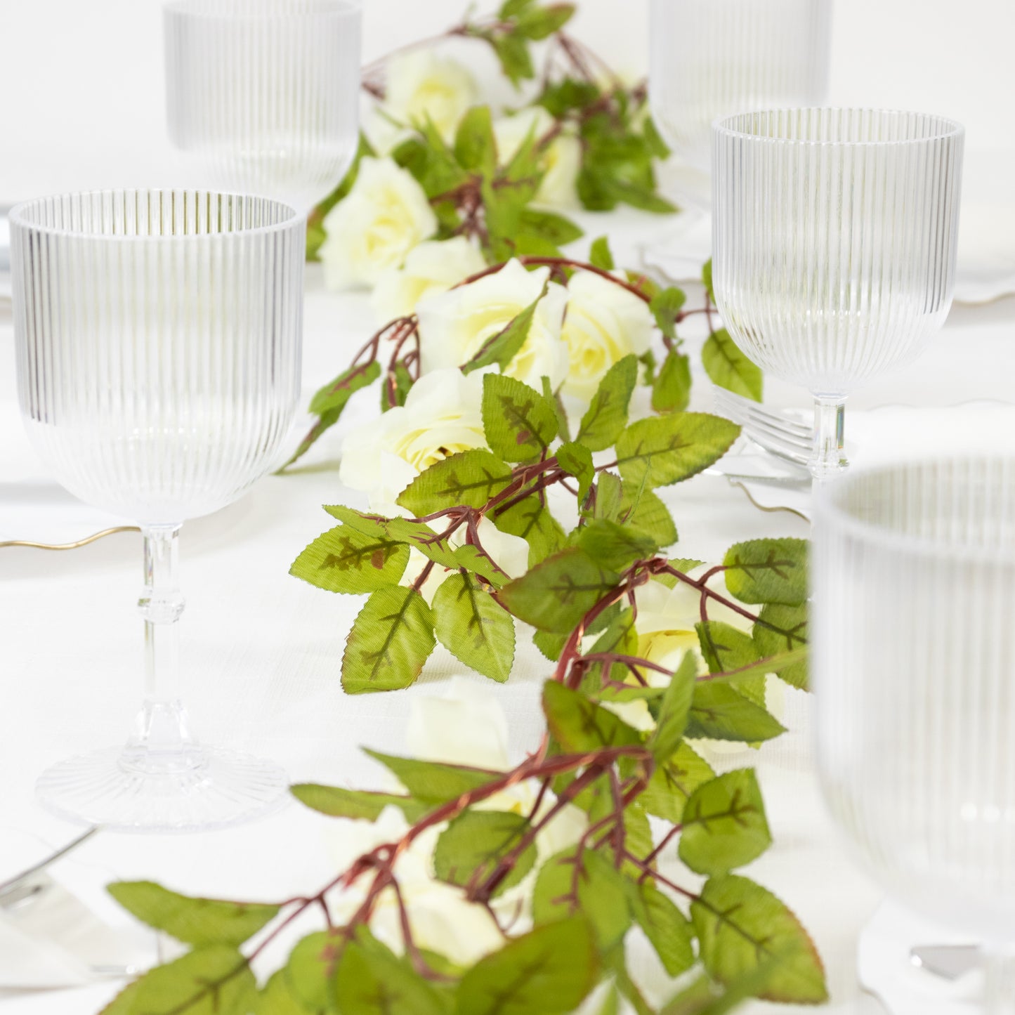 Warm white silk rose flower garland vine string lights on a table setting.