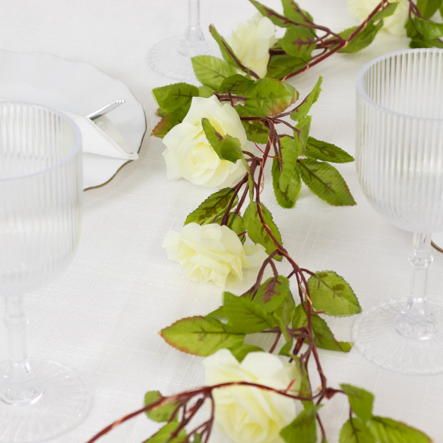 Warm white silk rose flower garland vine string lights on a table setting.